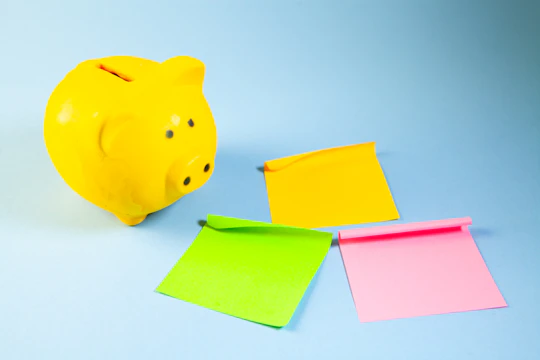A yellow piggy bank with three colorful sticky notes