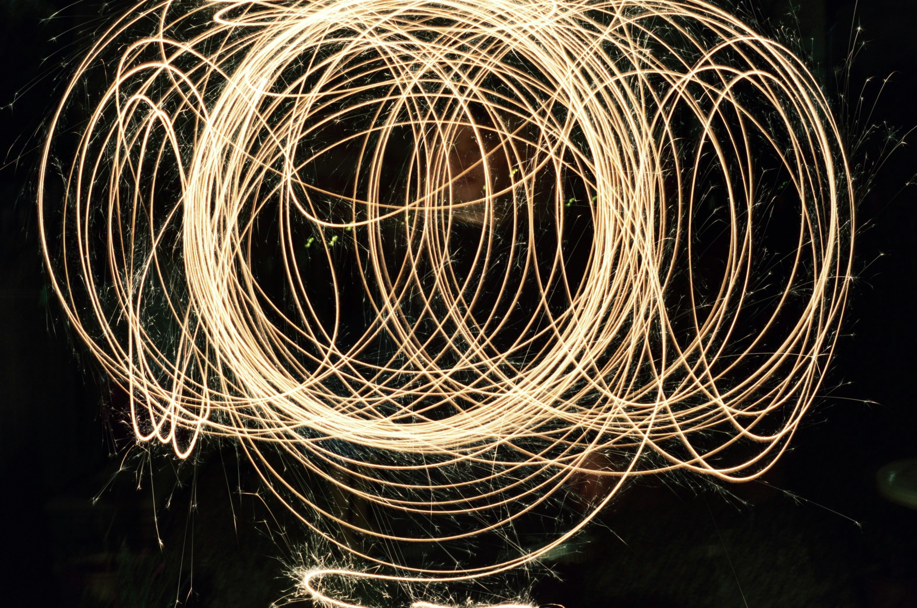 Light painting creates swirling golden circles against black