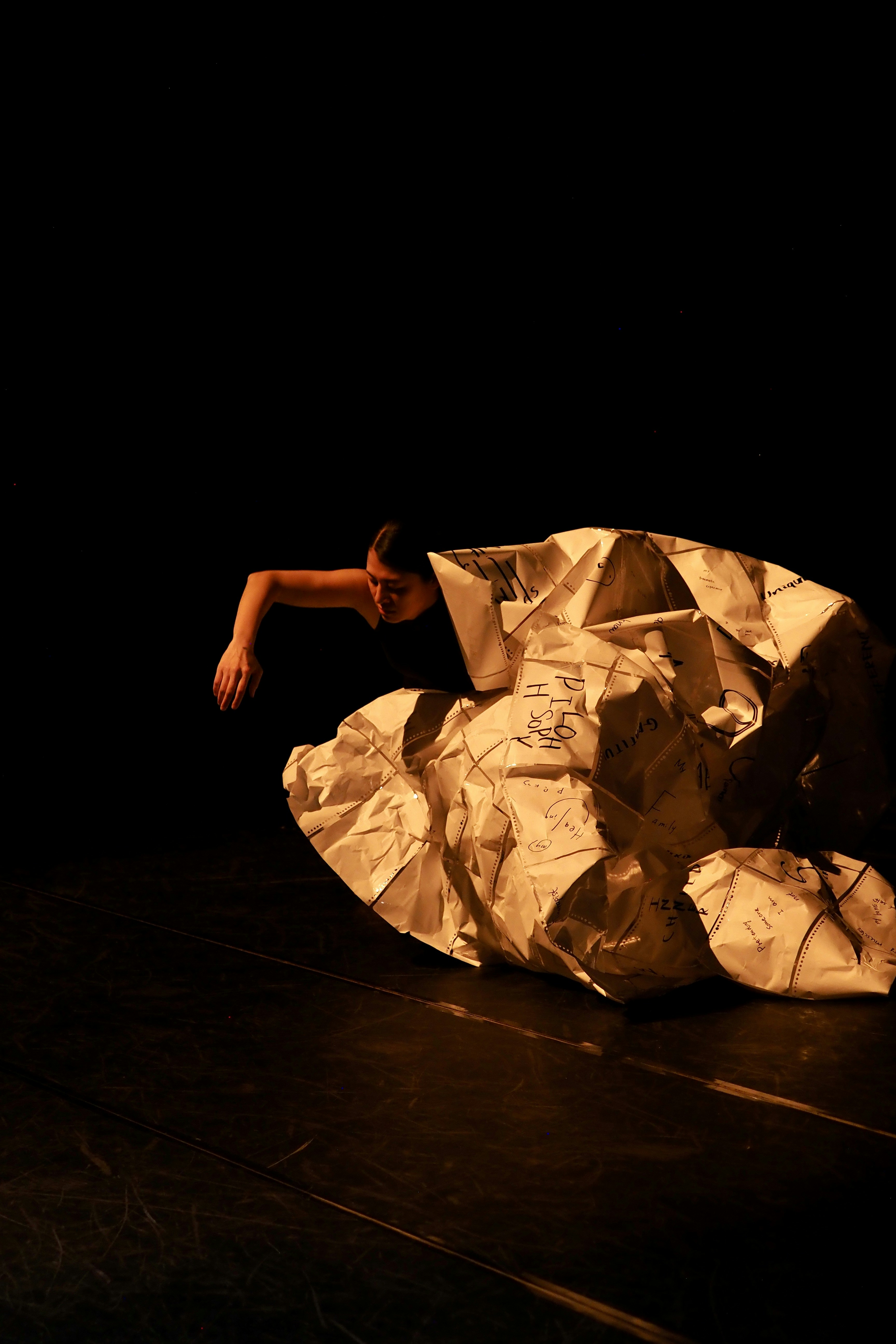 Dancer emerges from crumpled paper on stage