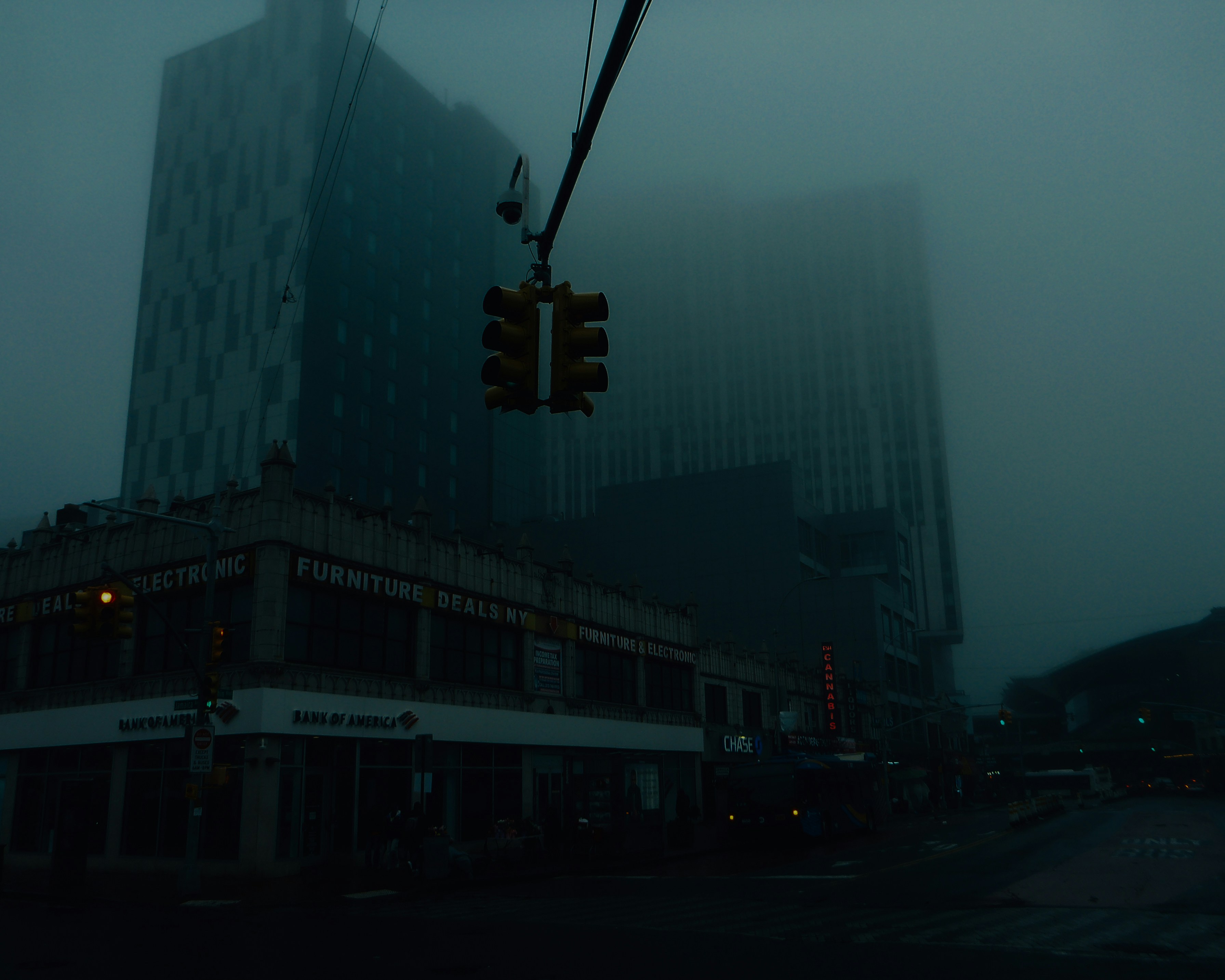 Foggy cityscape with buildings and traffic light.
