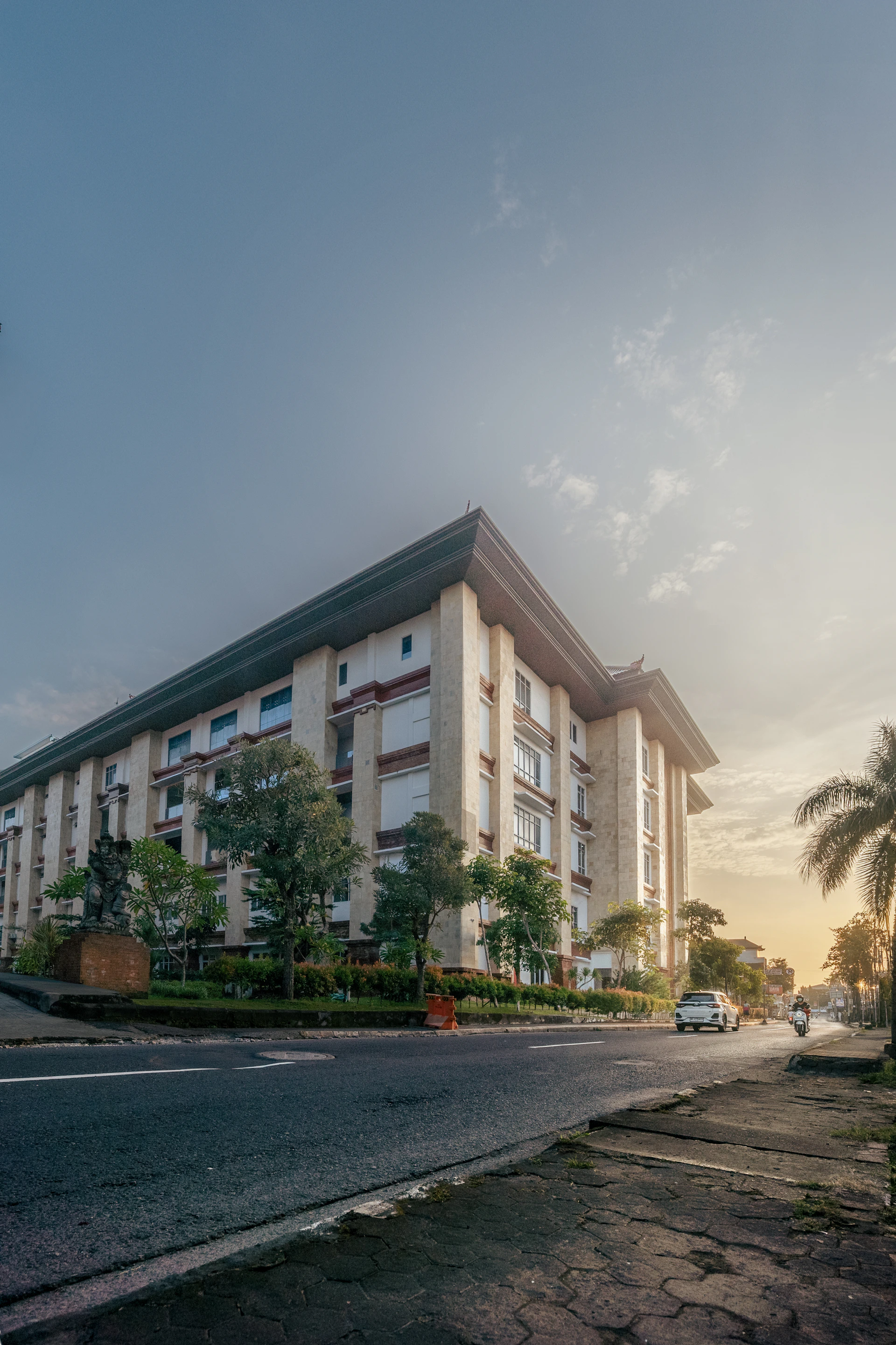 Modern building with trees and street during sunset.