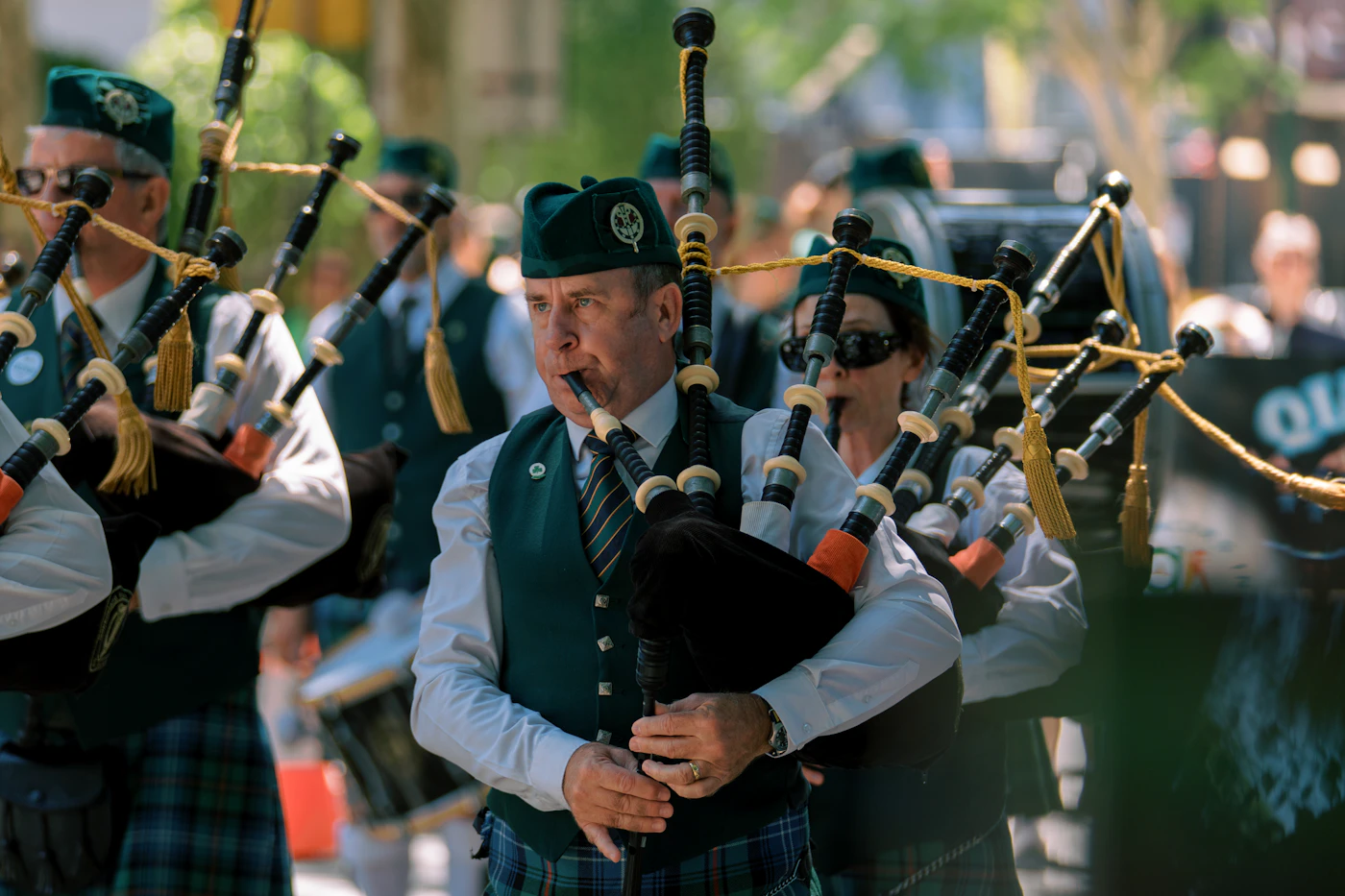 Marching bagpipe band in traditional kilts performing during a St. Patrick's Day parade