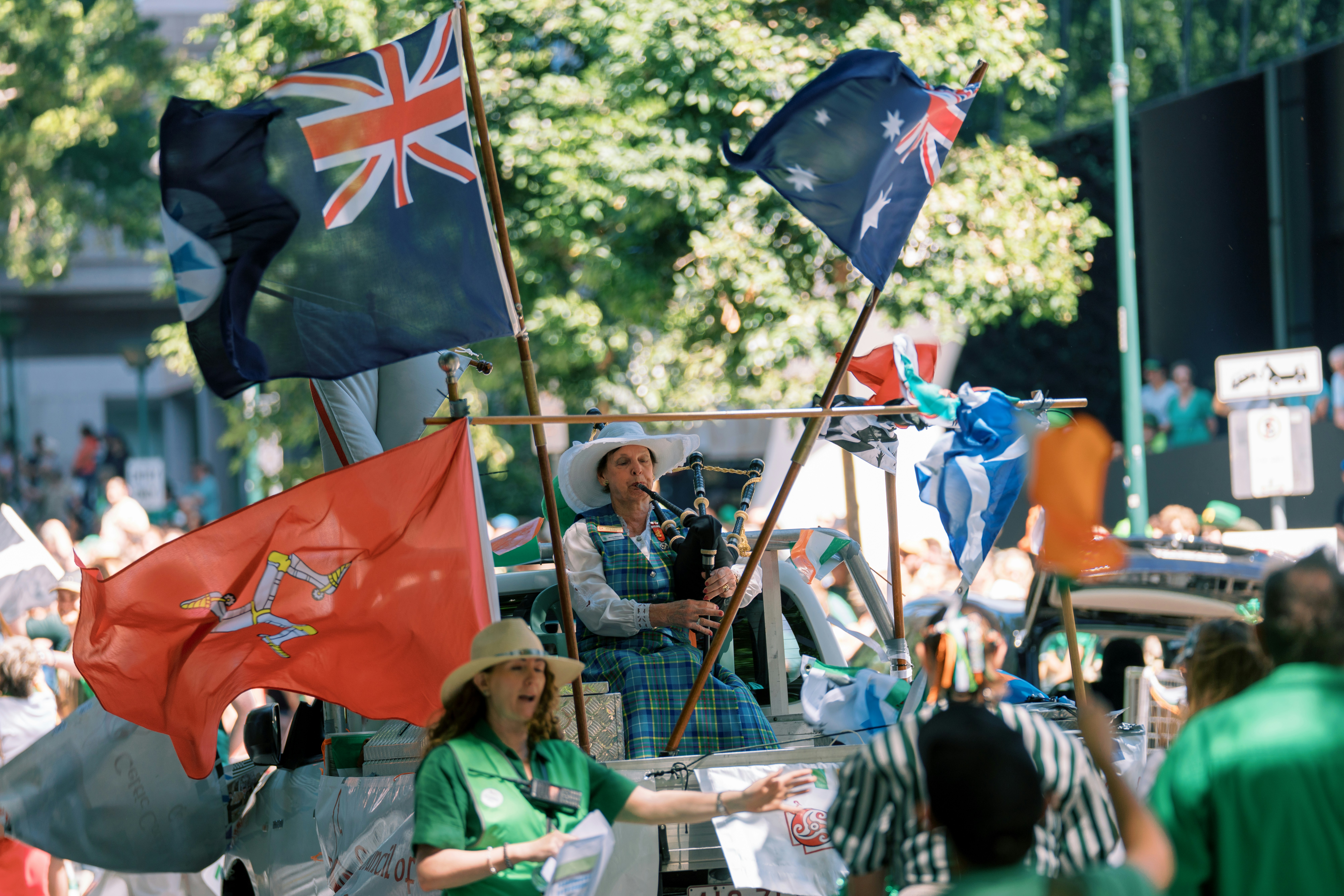 People wave australian and new zealand flags at a parade.