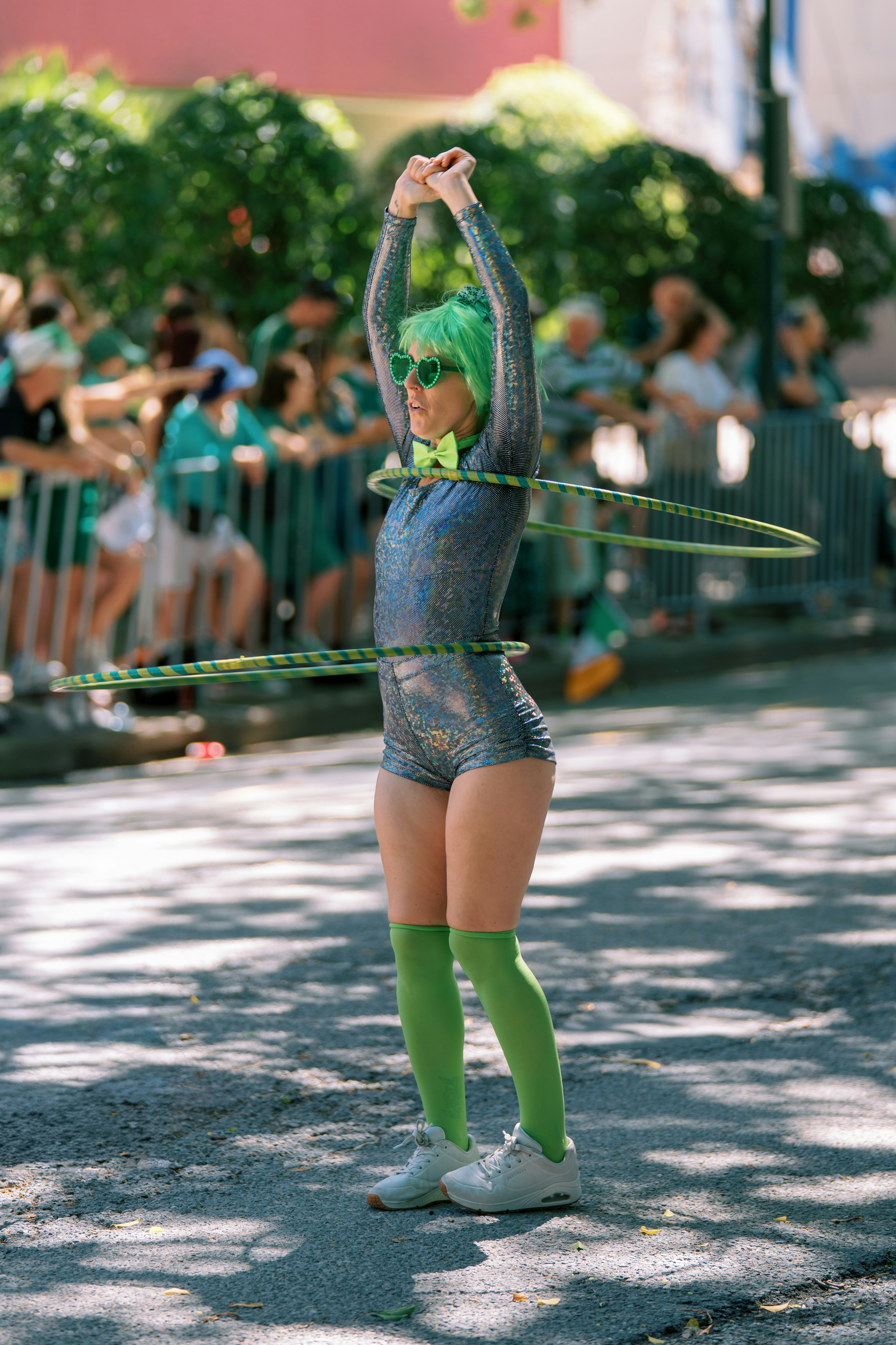 Wanita dengan wig hijau hula hooping dengan dua lingkaran