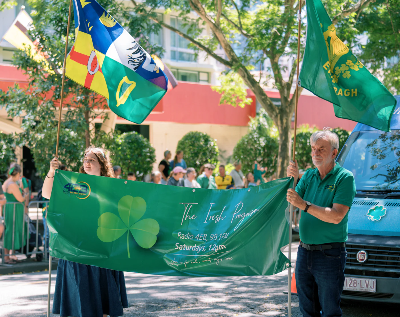 People carrying Irish flags and a shamrock banner during a St. Patrick's Day parade