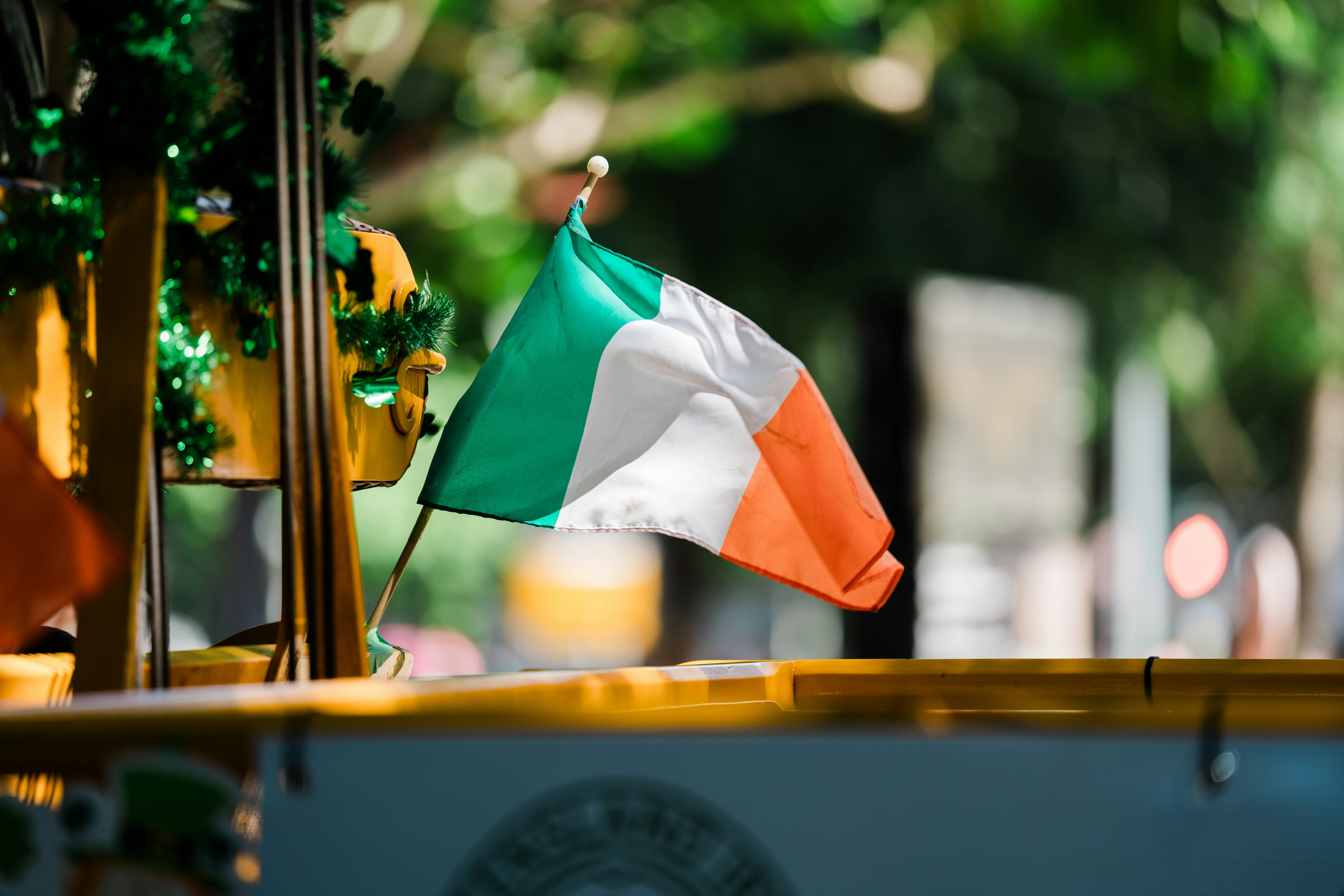 Eine irische Flagge weht sanft draußen mit verschwommenem Hintergrund.