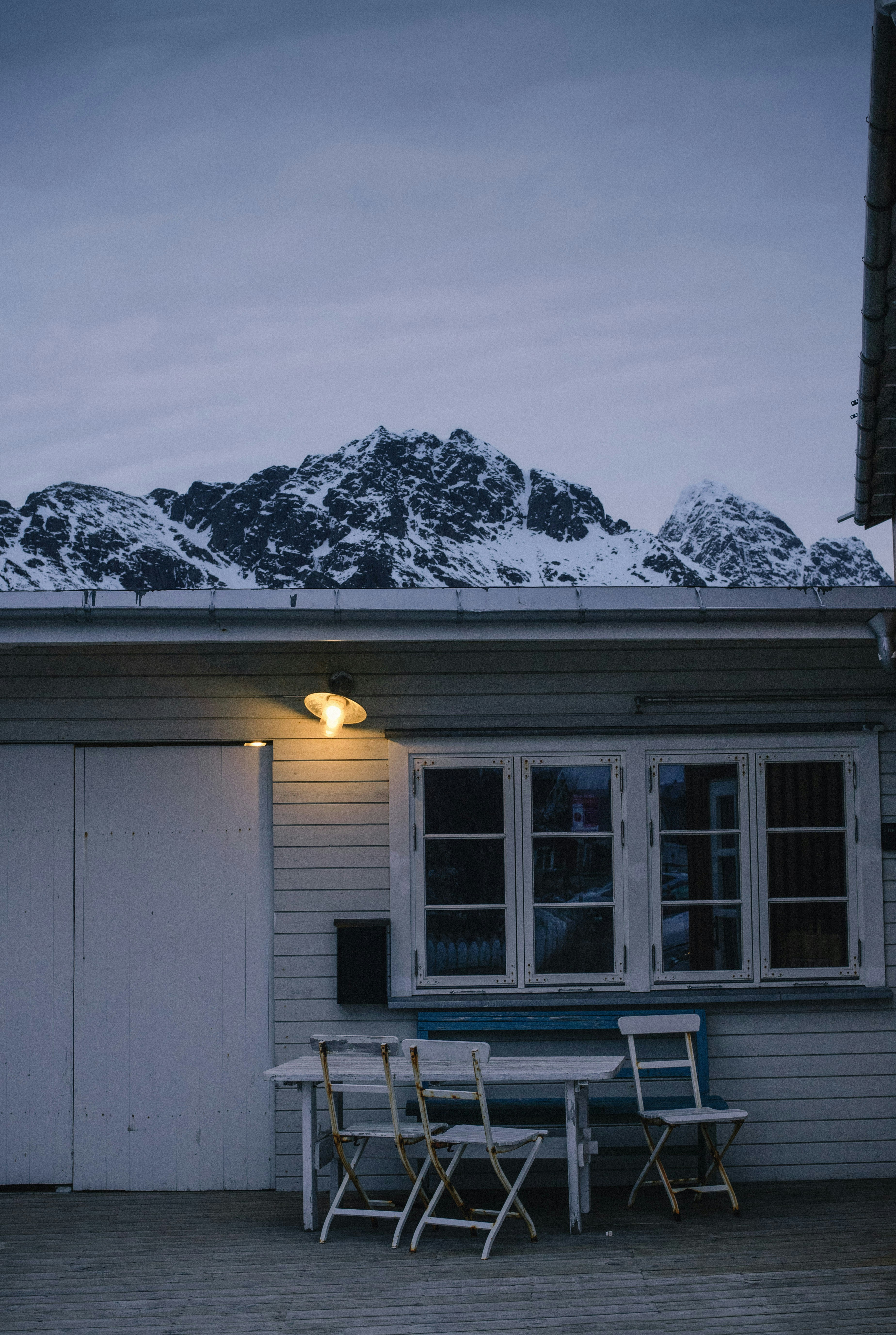 Montañas nevadas detrás de una pequeña casa al anochecer