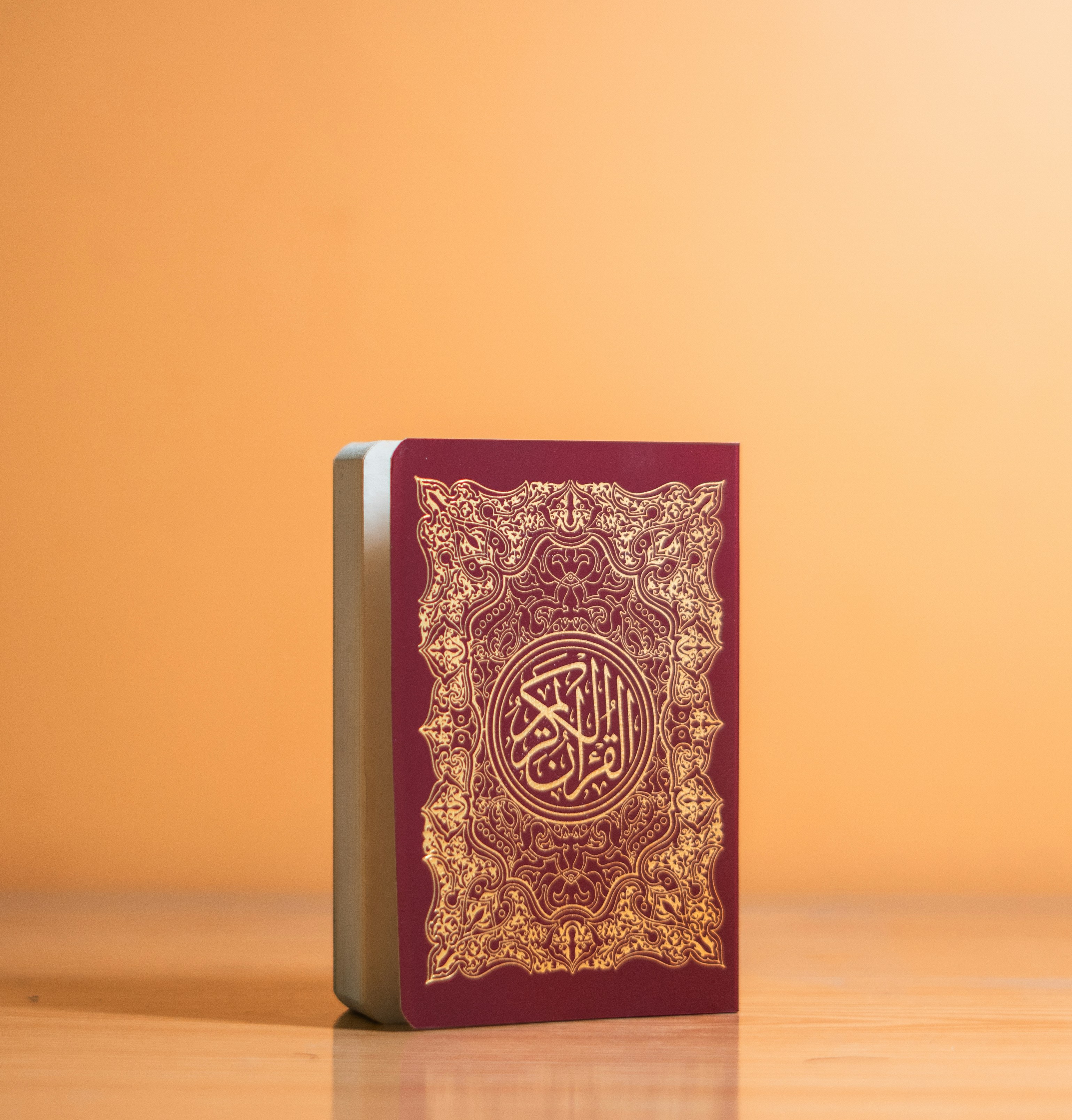 A burgundy quran with gold ornate design