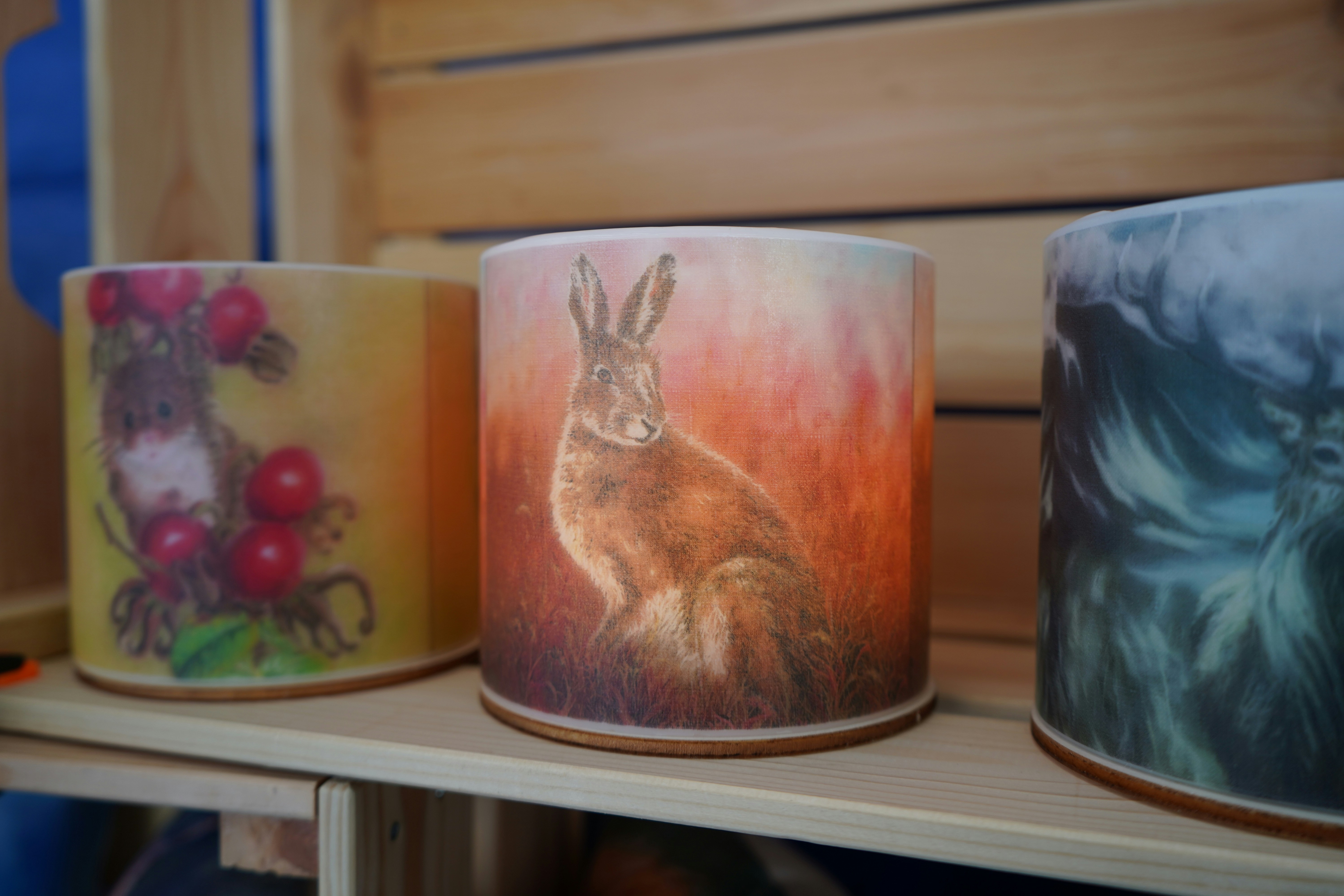 Three decorative cylindrical objects with nature-themed designs