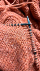 Knitting with orange yarn and metal needles