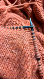 Knitting with orange yarn and metal needles