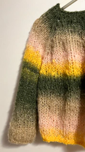 A colorful striped knitted sweater hanging on a wall