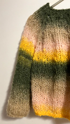 A colorful striped knitted sweater hanging on a wall