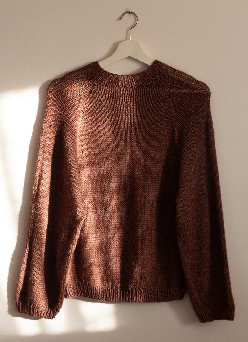 Brown knitted sweater on a white hanger