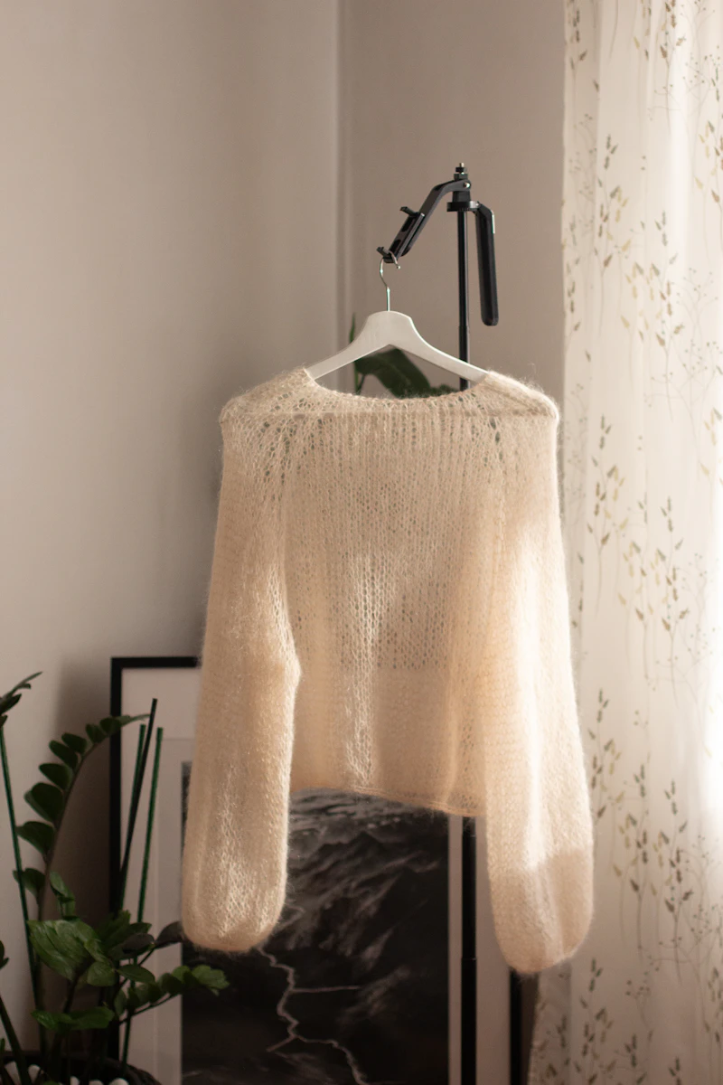 Cream fuzzy sweater on a hanger