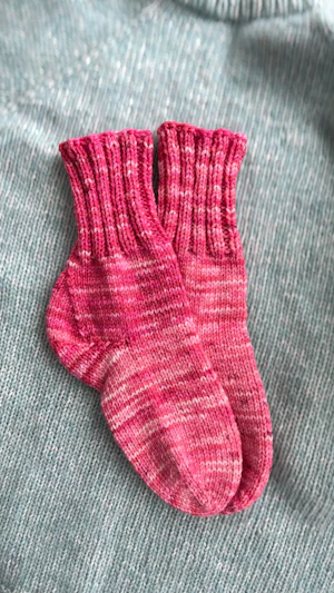 pink hand-knitted socks on a blue jumper