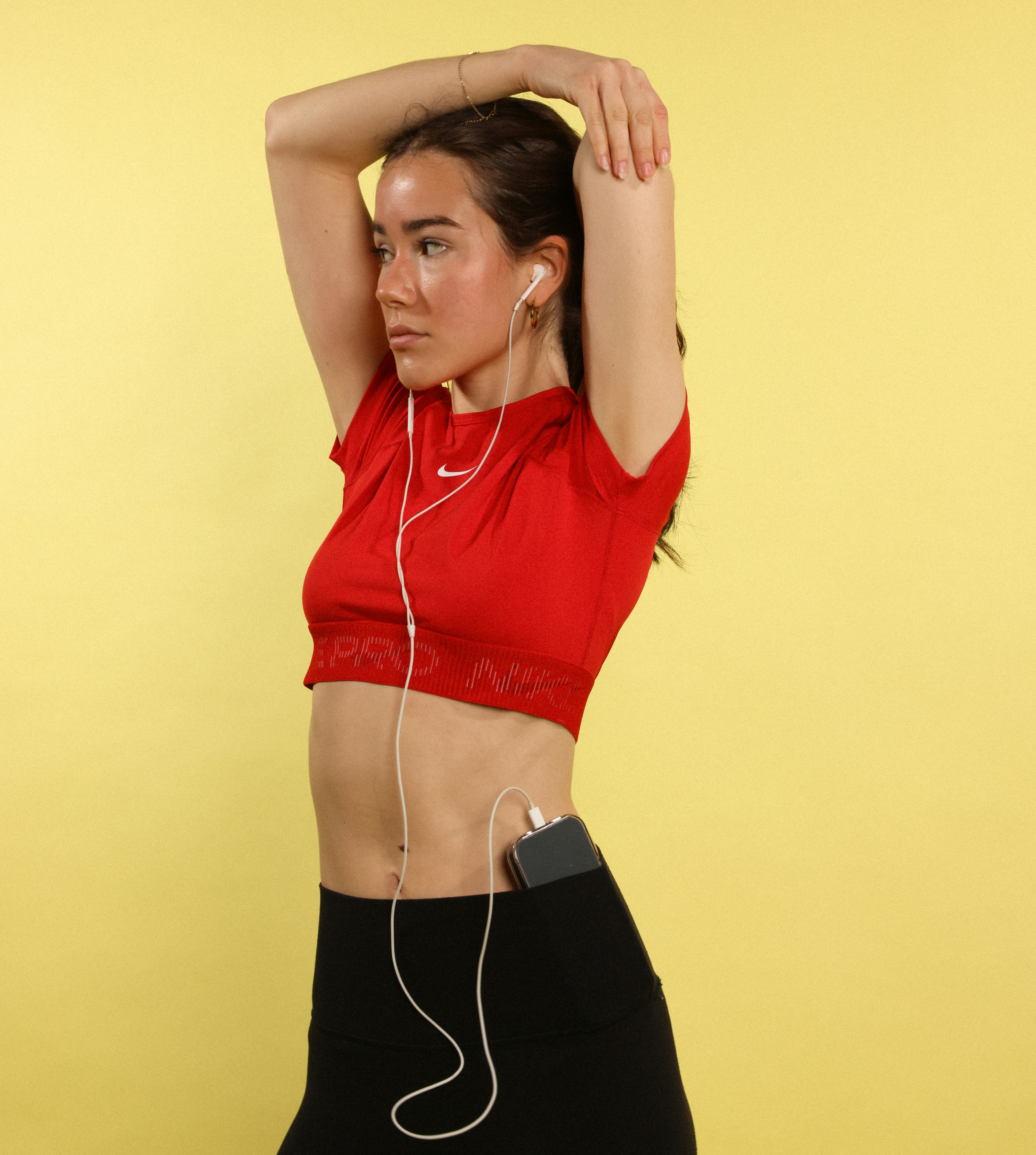 Woman stretching with headphones on yellow background