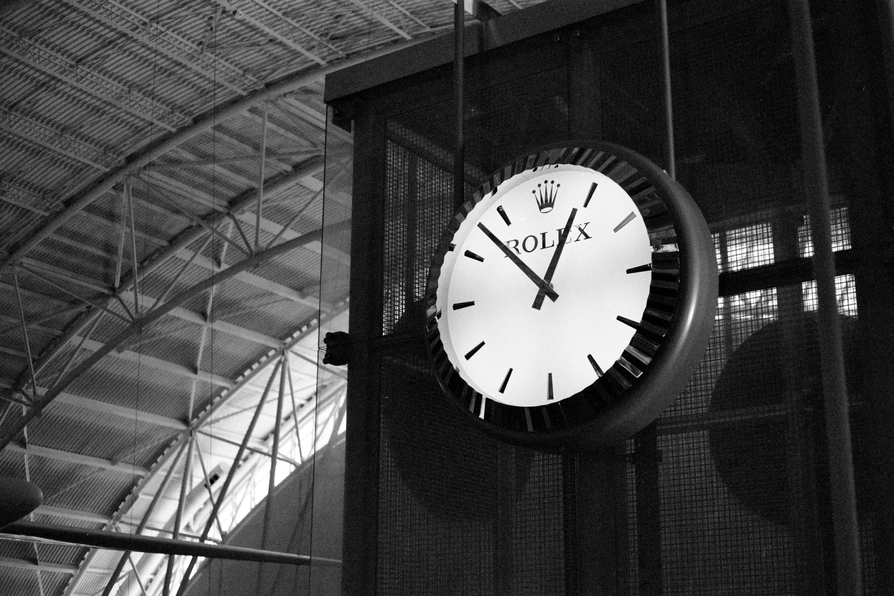 A large rolex clock hanging indoors