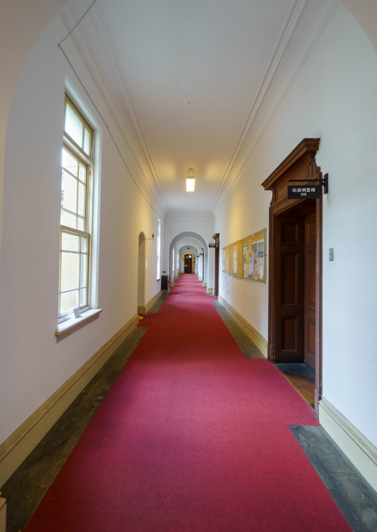Lorong panjang berkarpet merah dengan lengkungan.