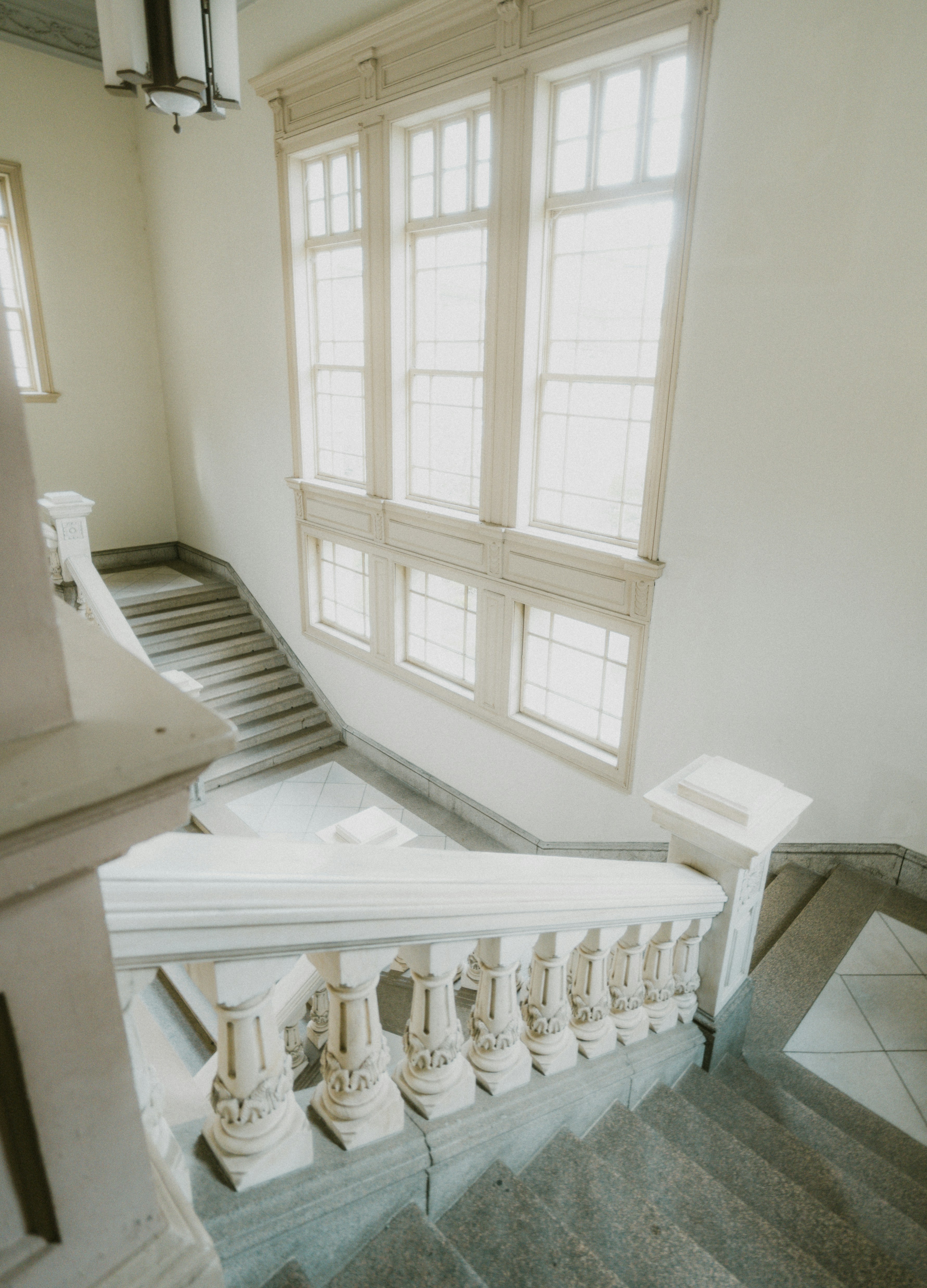 Elegant staircase with ornate balustrade and large windows