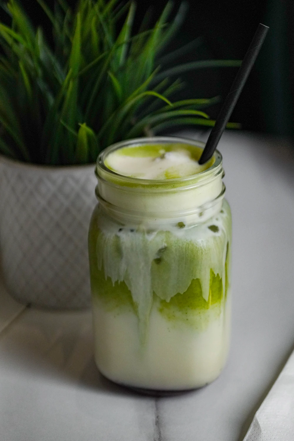 An iced green tea latte in a glass with a straw