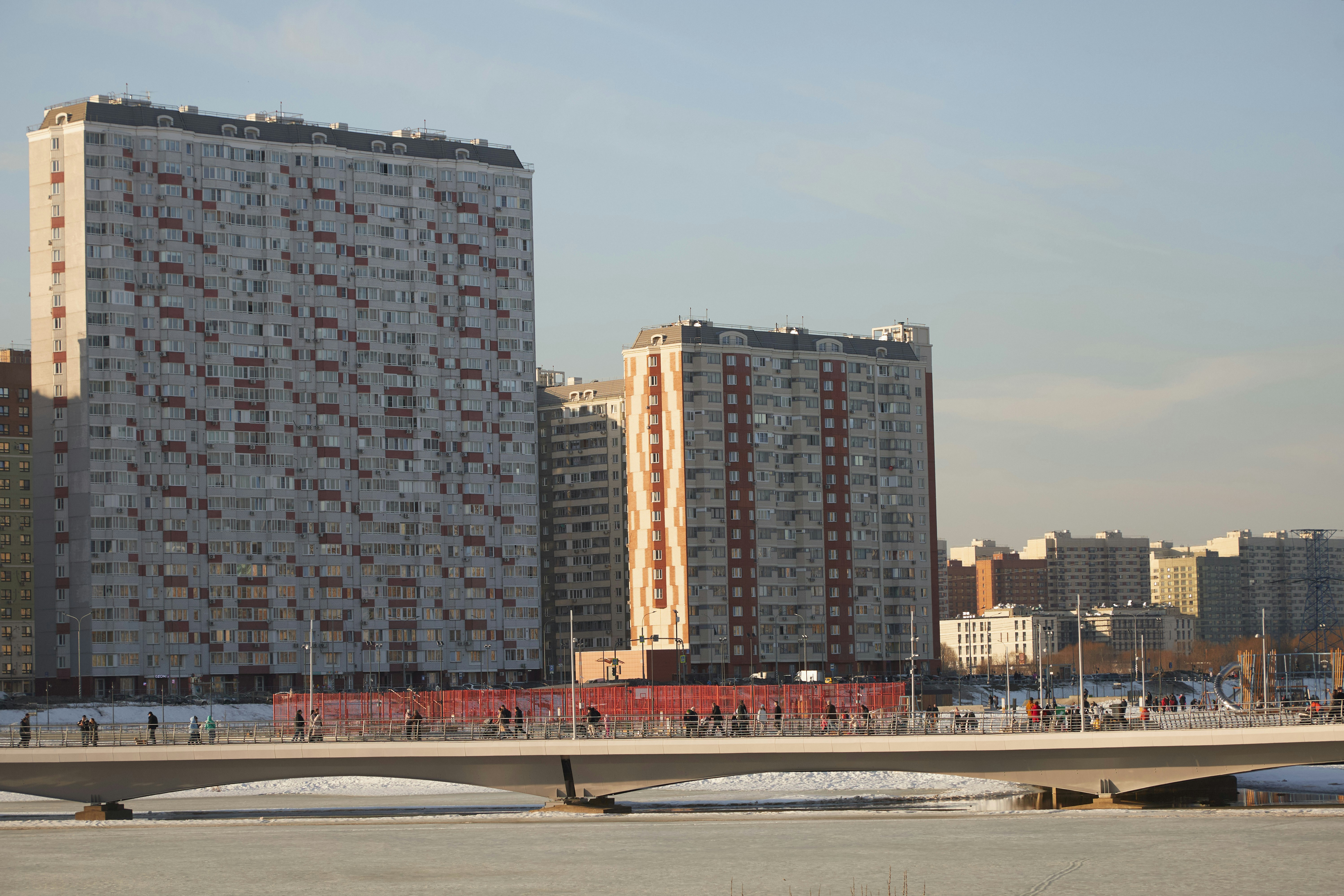 Two tall apartment buildings with a bridge in front.