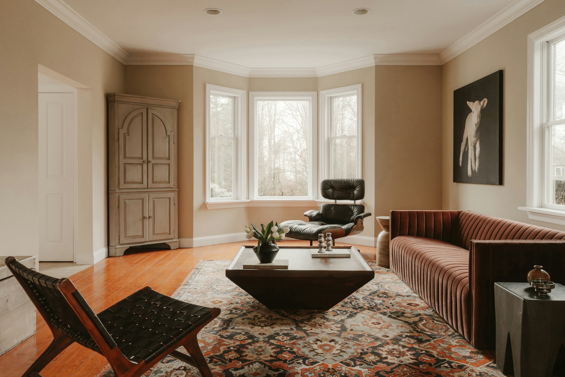Modern living room with warm-toned stylish furniture and large windows