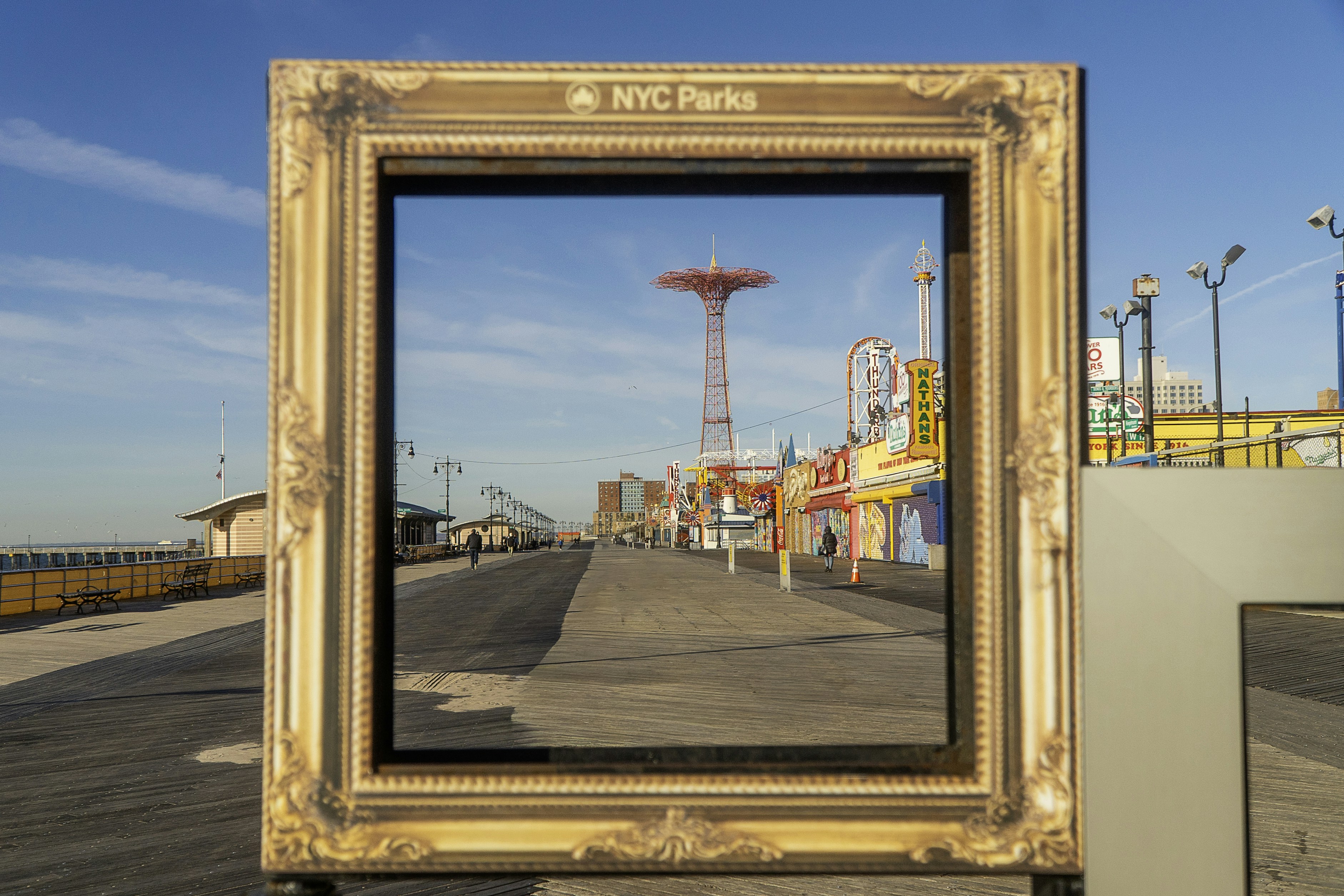 Coney island boardwalk framed by a large ornate gold frame.