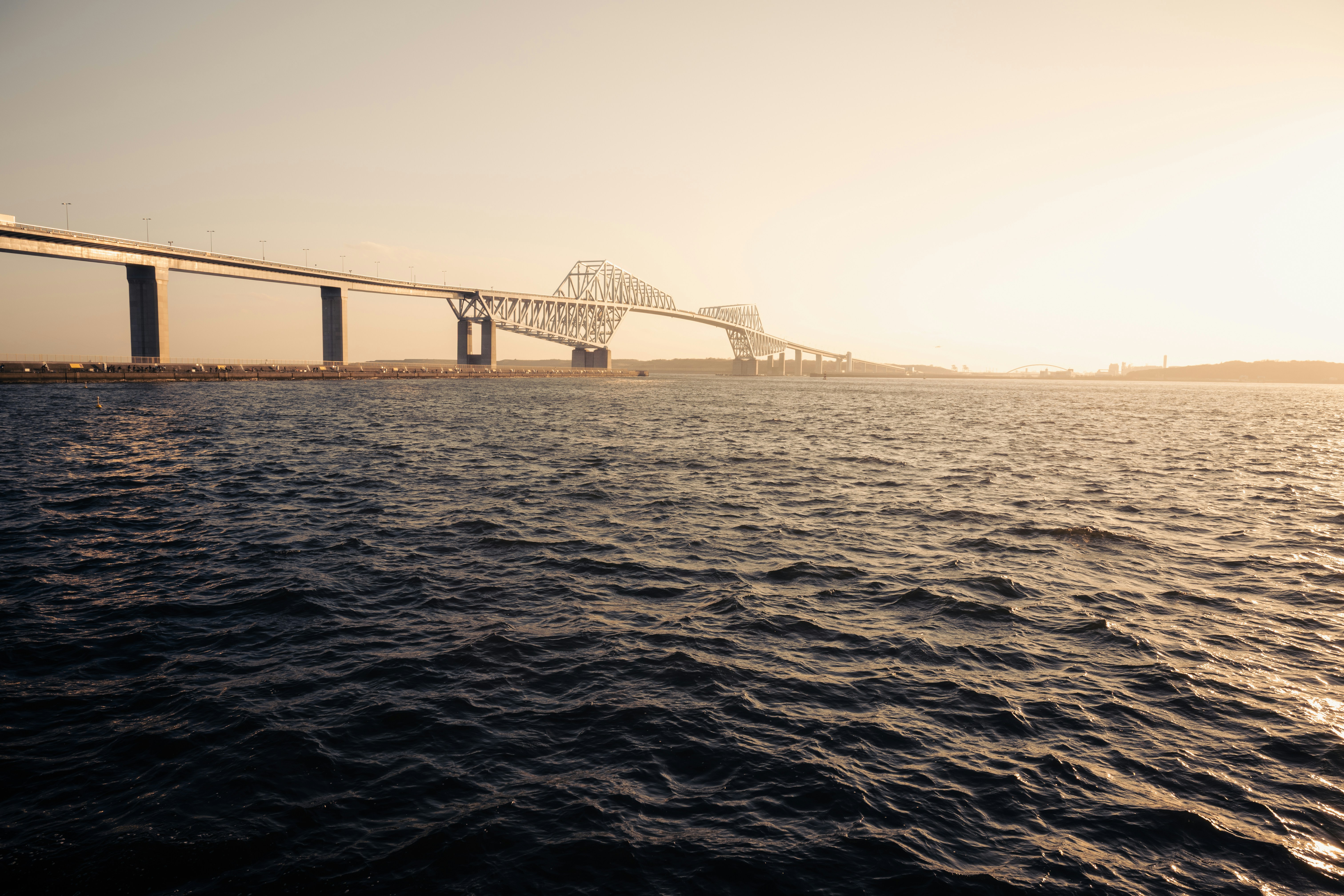 A modern bridge crosses a body of water at sunset.