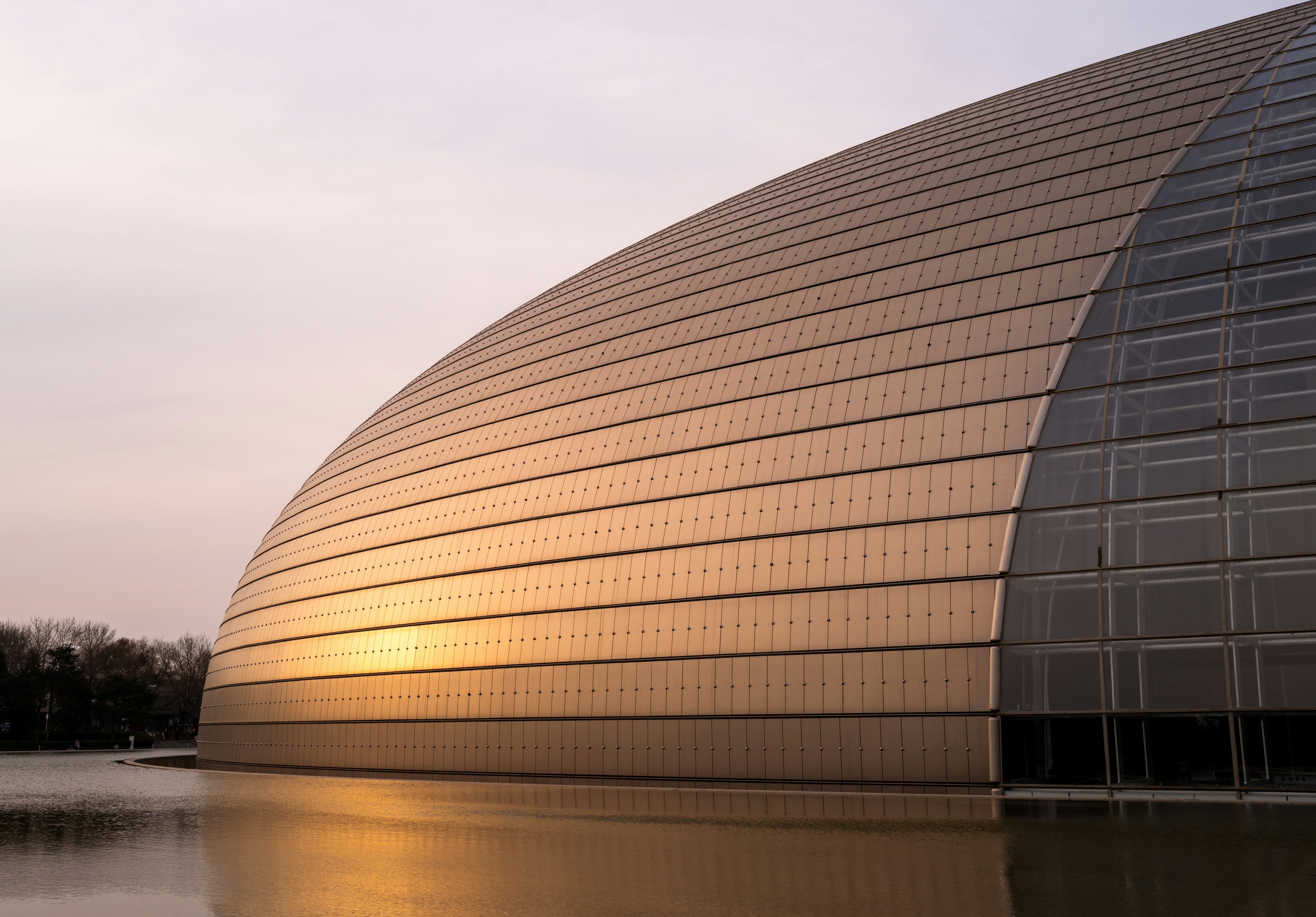 Bâtiment moderne à dôme réfléchi dans l’eau au coucher du soleil