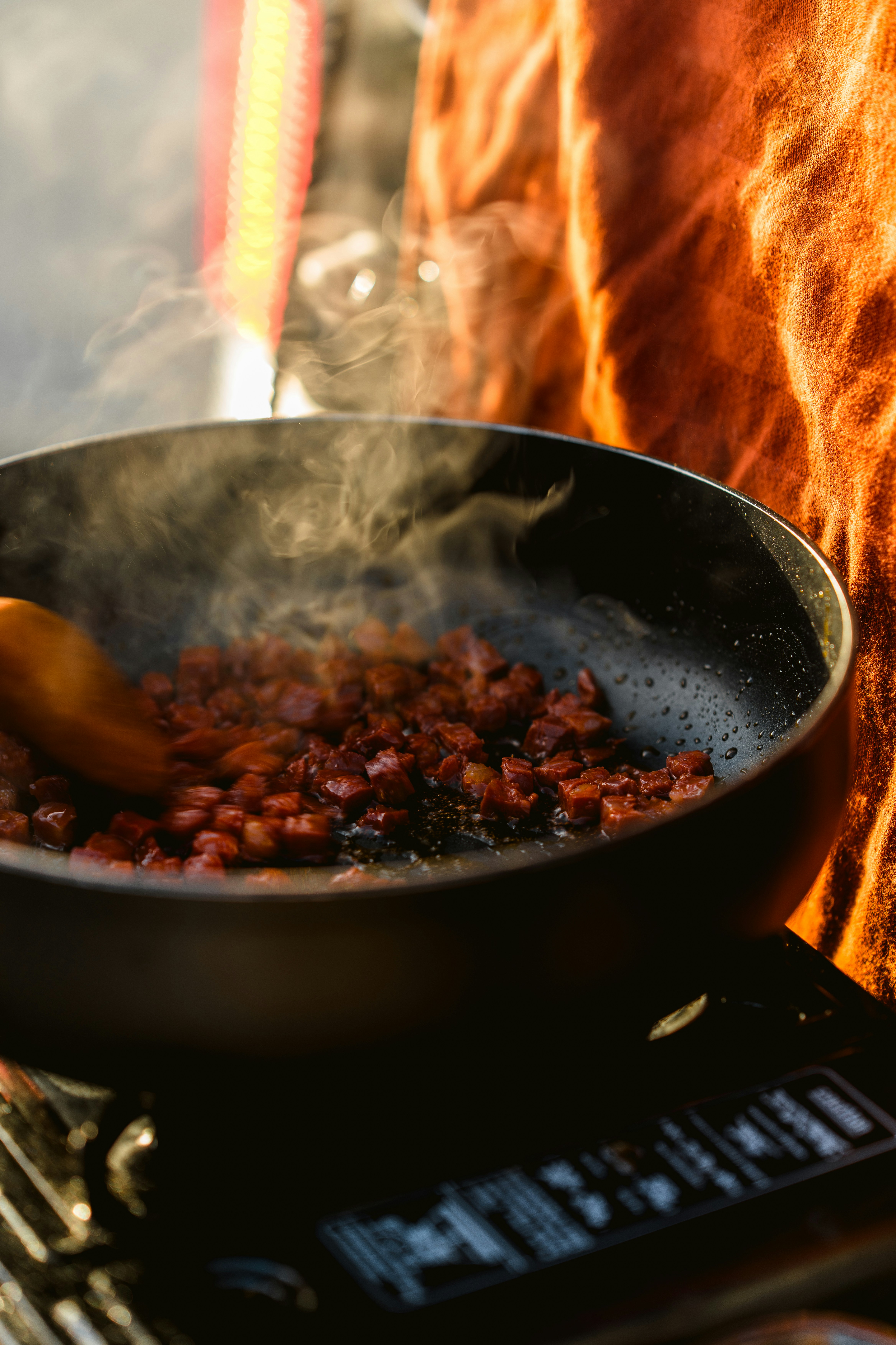 Bacon is frying in a pan with steam rising.