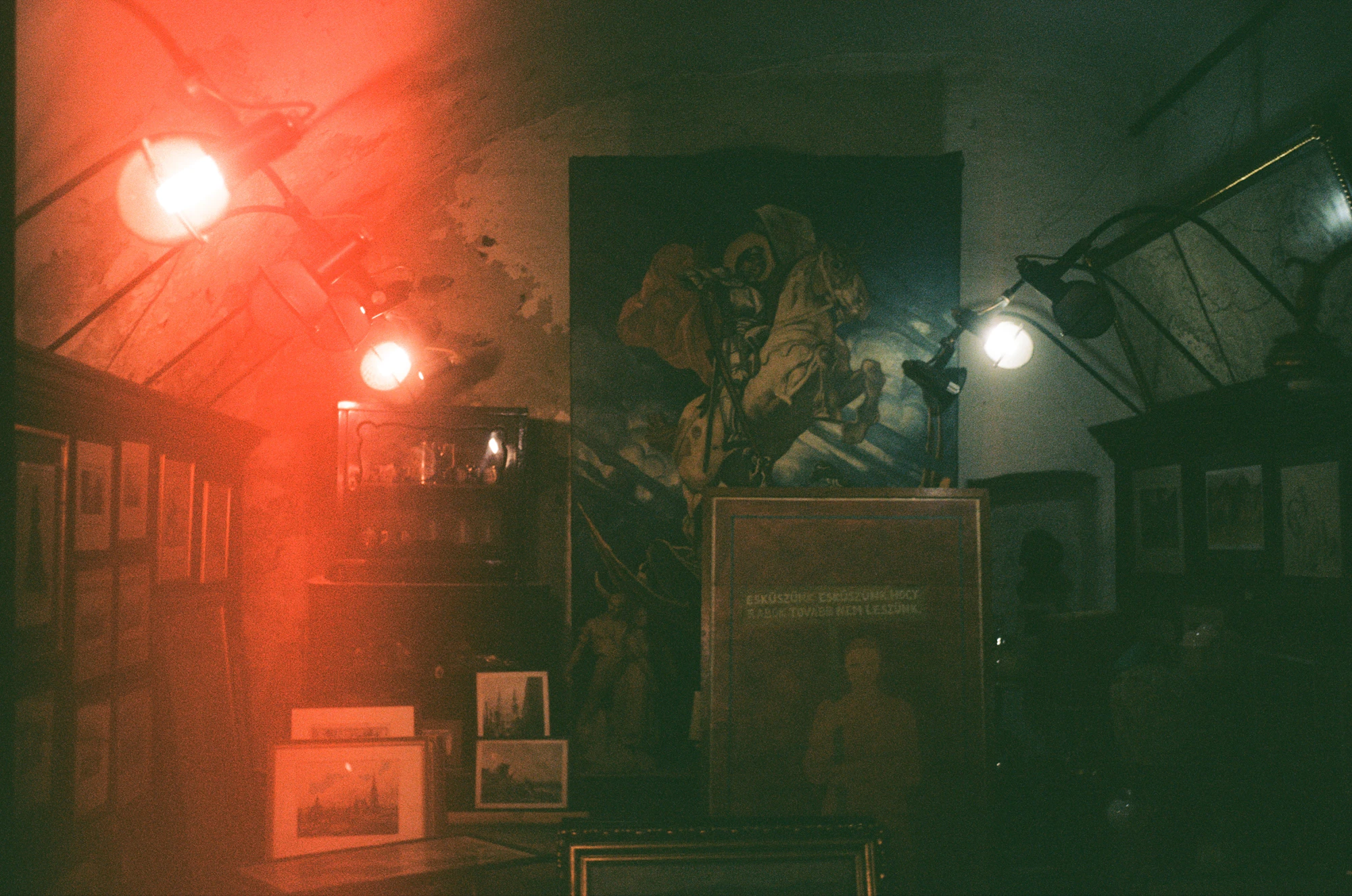 Dimly lit gallery interior with artwork and hanging lights