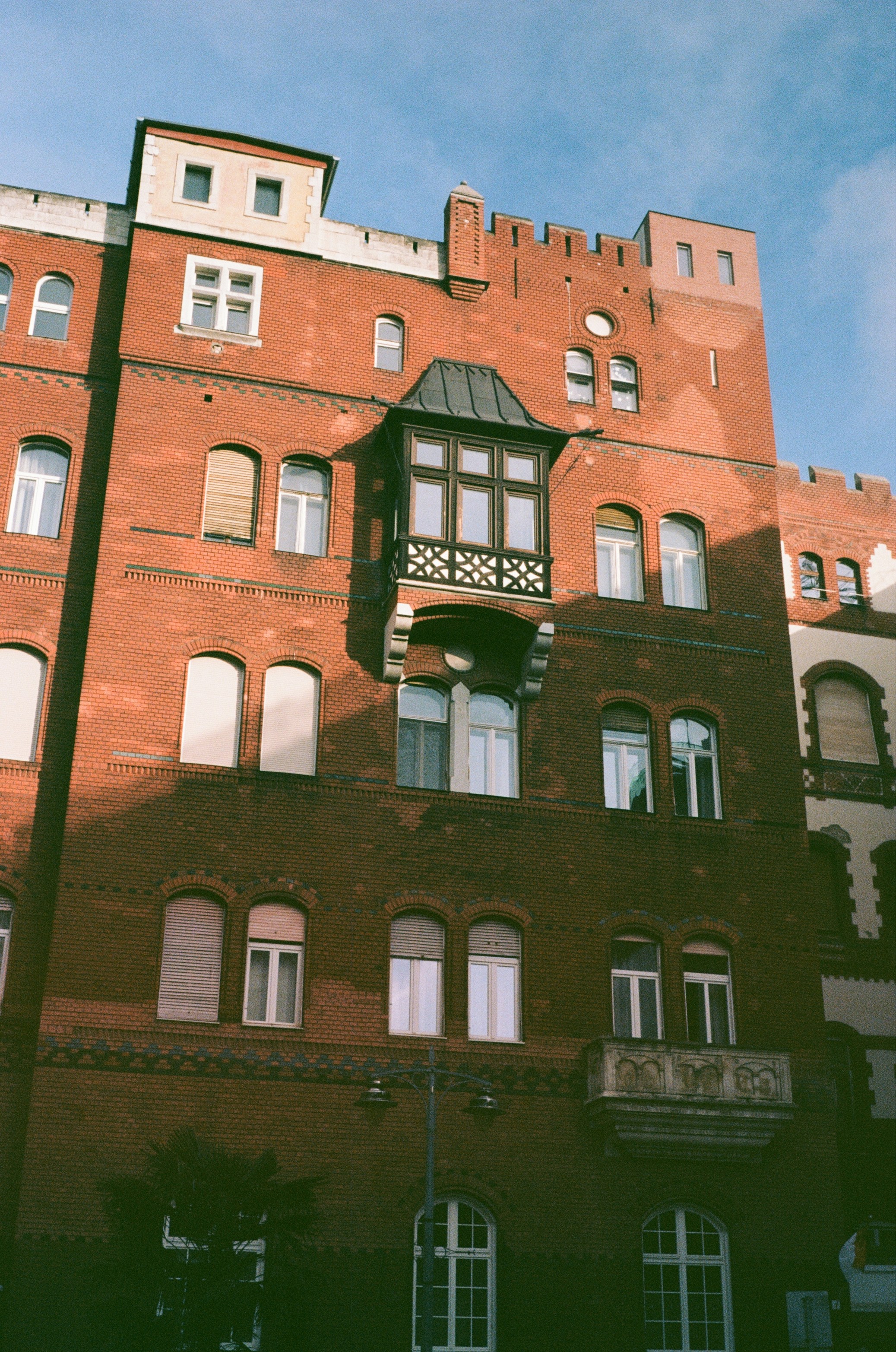 Red brick building with many windows and a balcony.