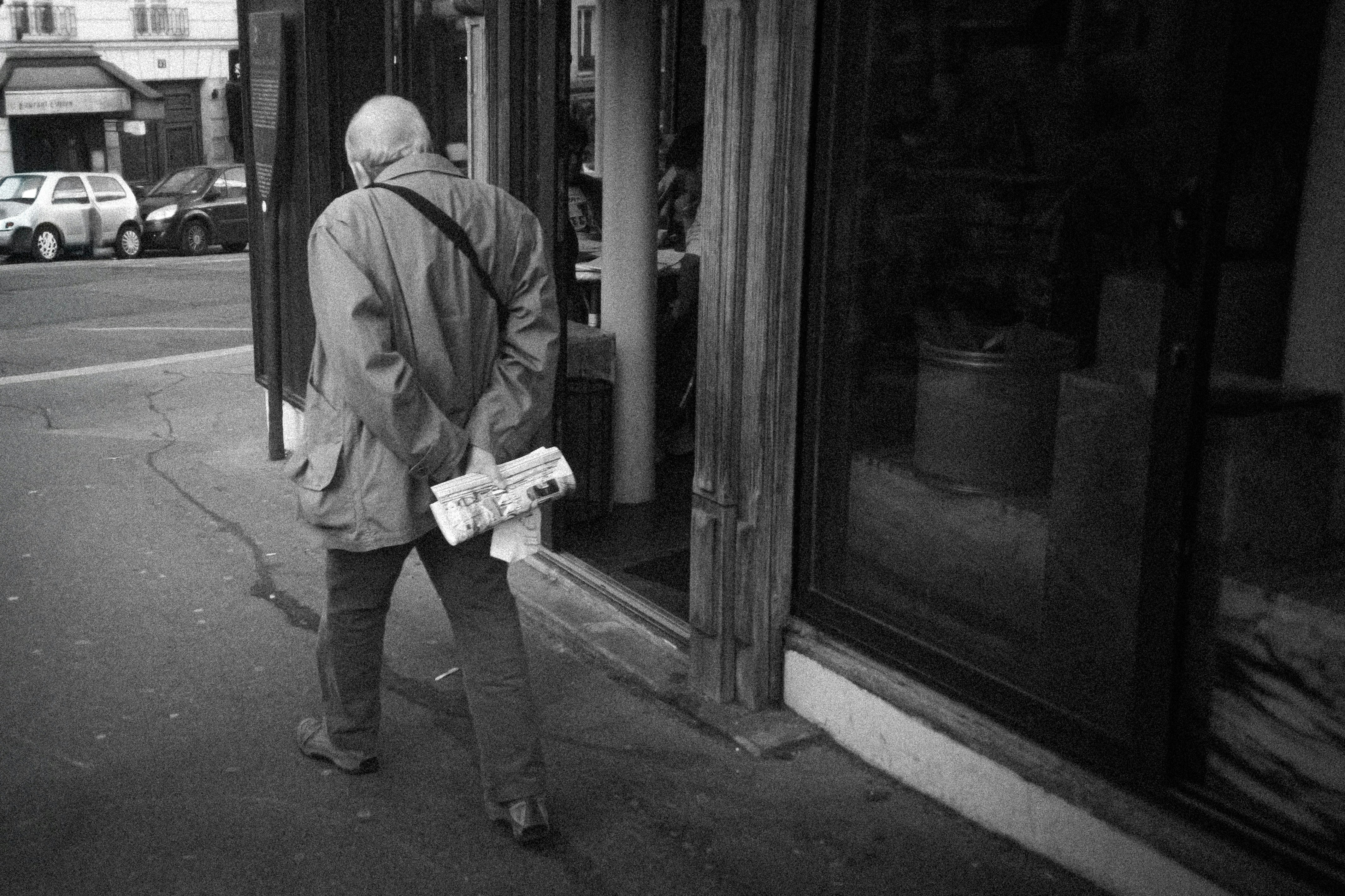 Man walking away holding newspapers