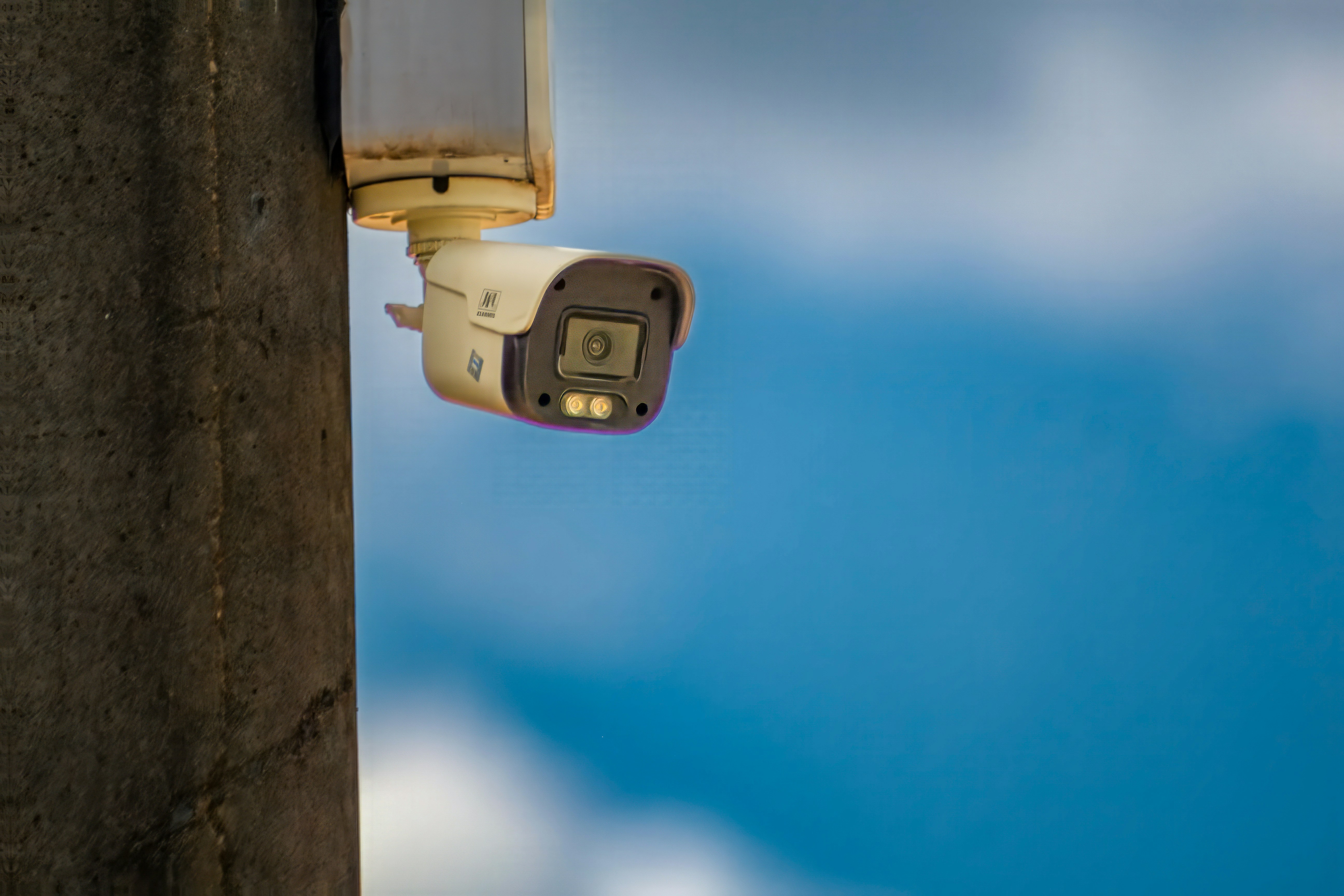 Telecamera di sicurezza montata su un palo con il cielo azzurro.