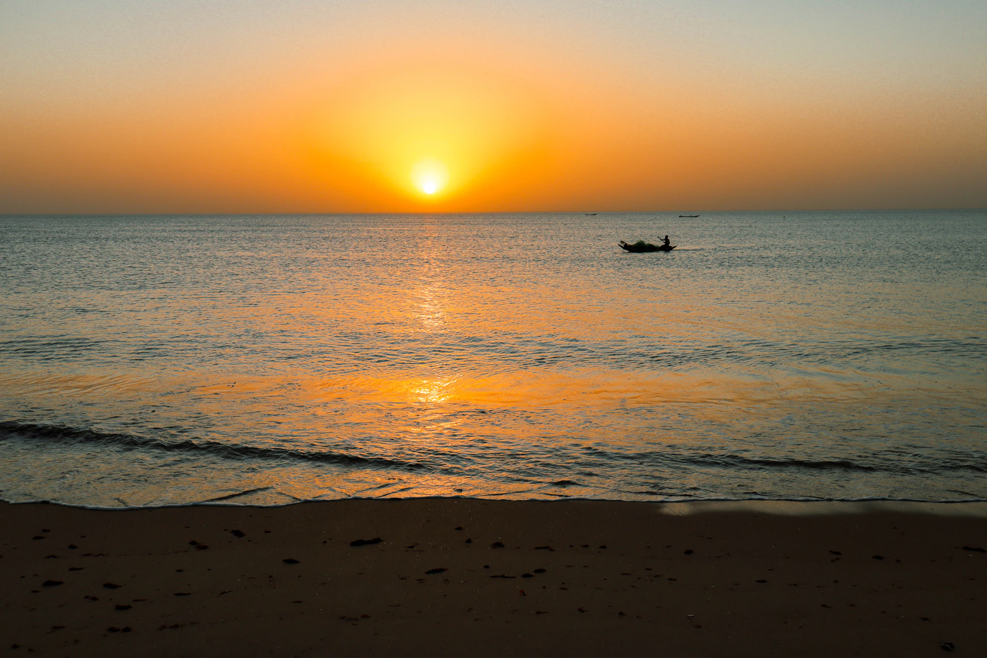 A lone boat on the ocean at sunset