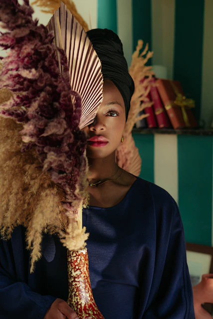 Woman in turban peeking through large dried flowers.