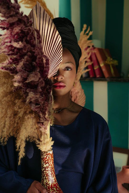 Woman in turban peeking through large dried flowers.
