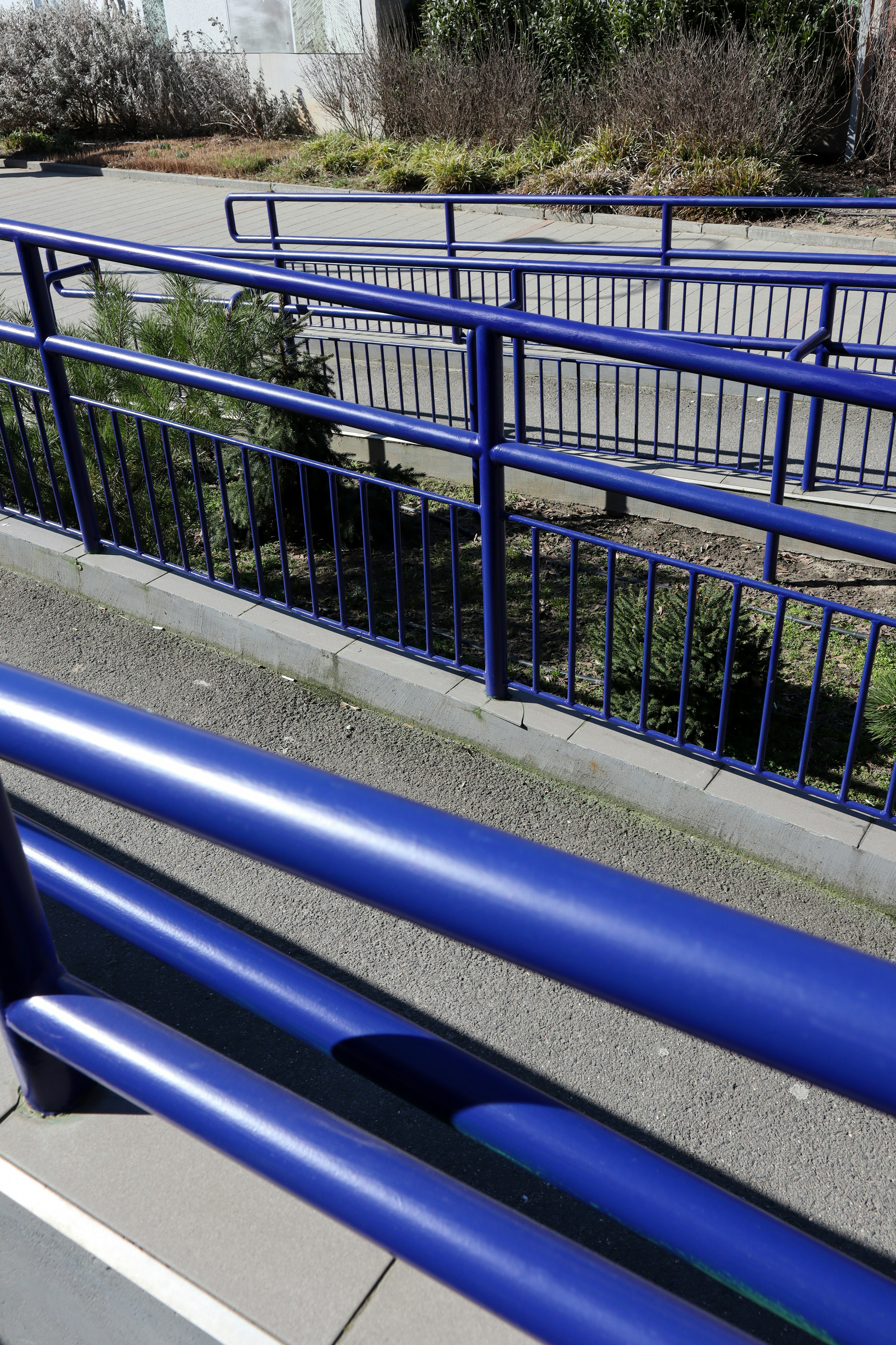 Rambarde métallique bleue à côté d’une passerelle pavée.