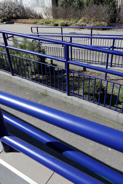 Blue metal railing next to a paved walkway.