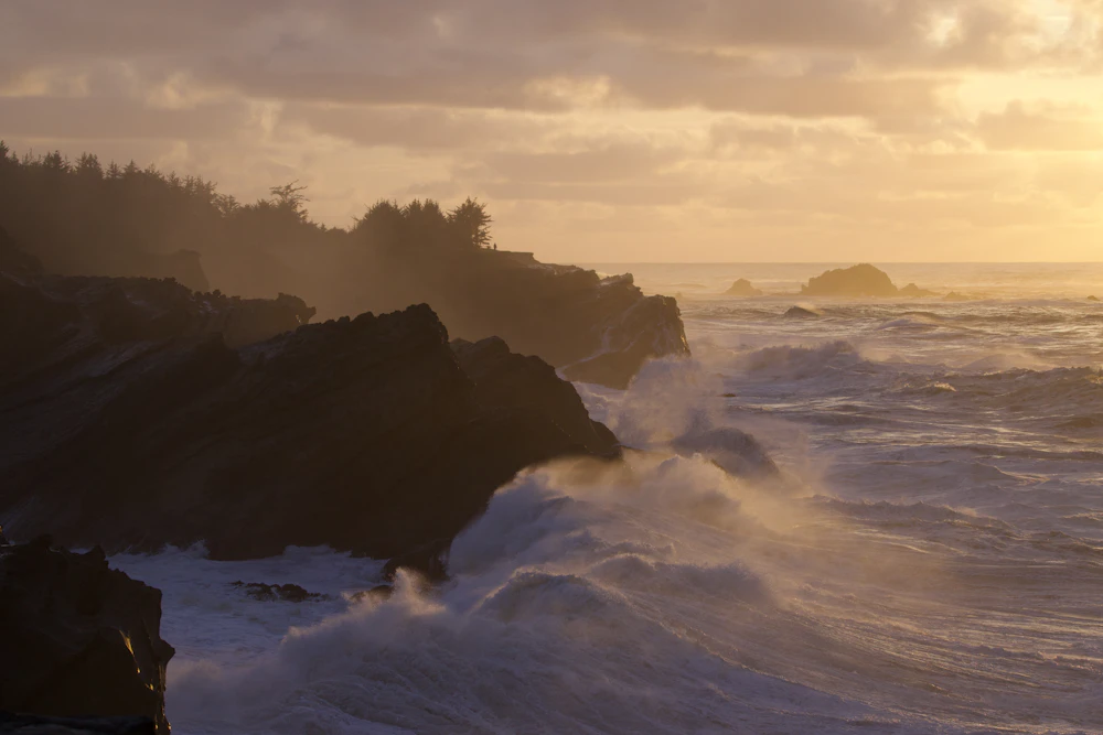 Waves crashing against rocky cliffs at sunset