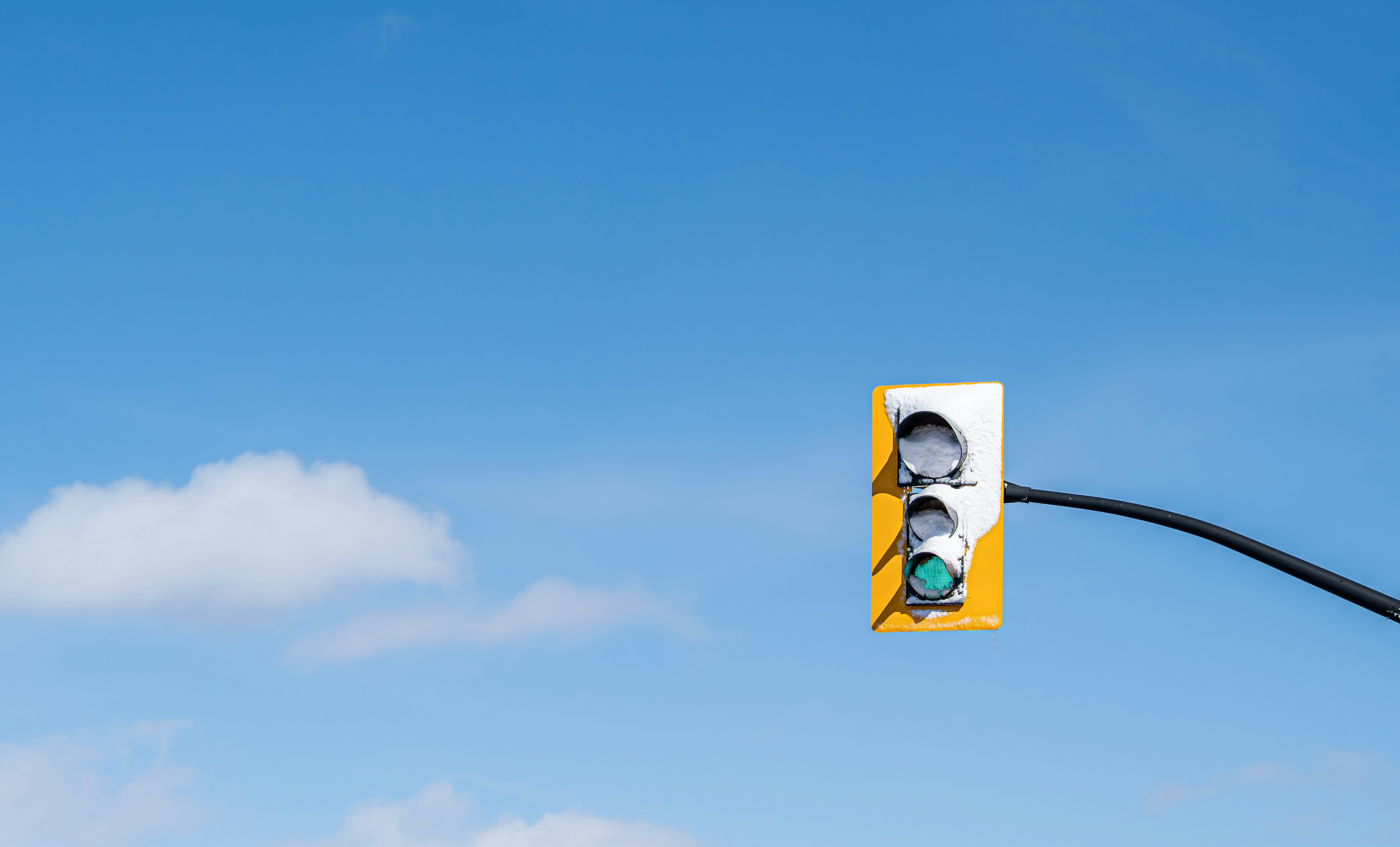 A traffic light shows green against a blue sky.