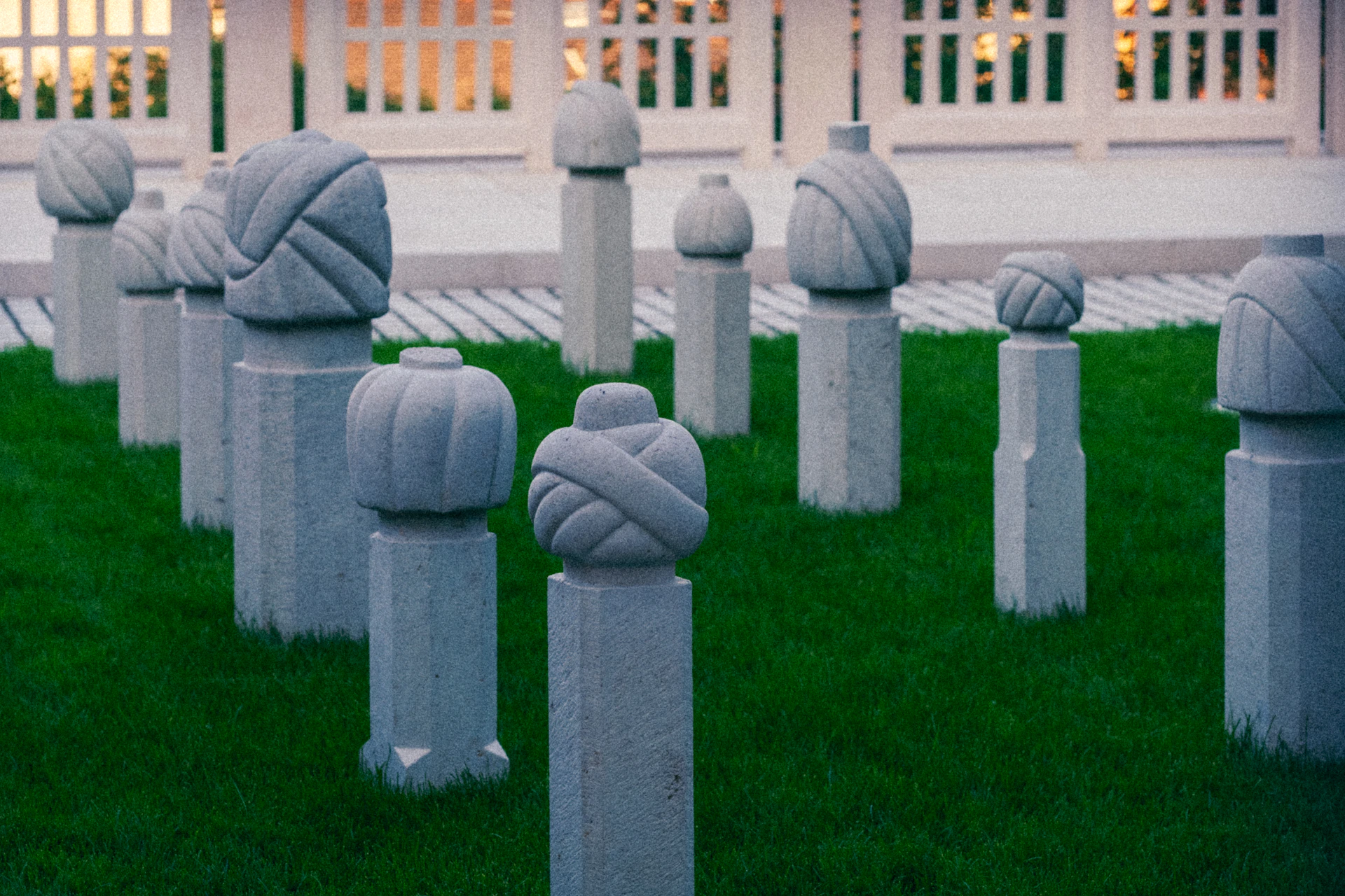 Stone grave markers with turban-like carvings on grass.