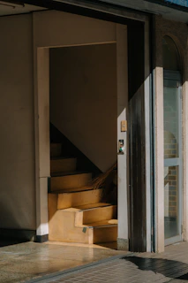 Sunlight streams onto a staircase through an open doorway