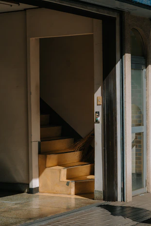 Sunlight streams onto a staircase through an open doorway