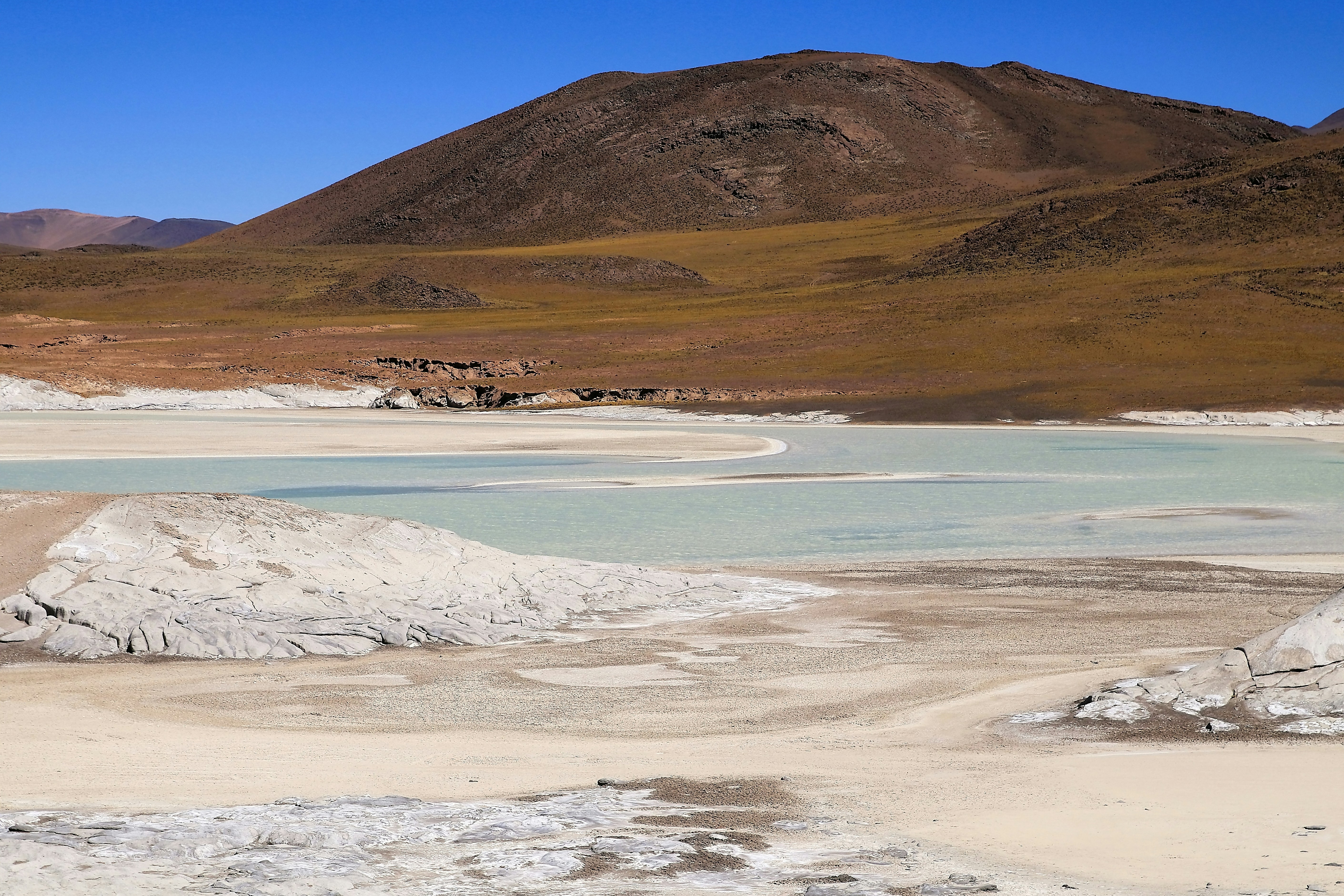 Uma vasta paisagem desértica com um lago azul pálido.