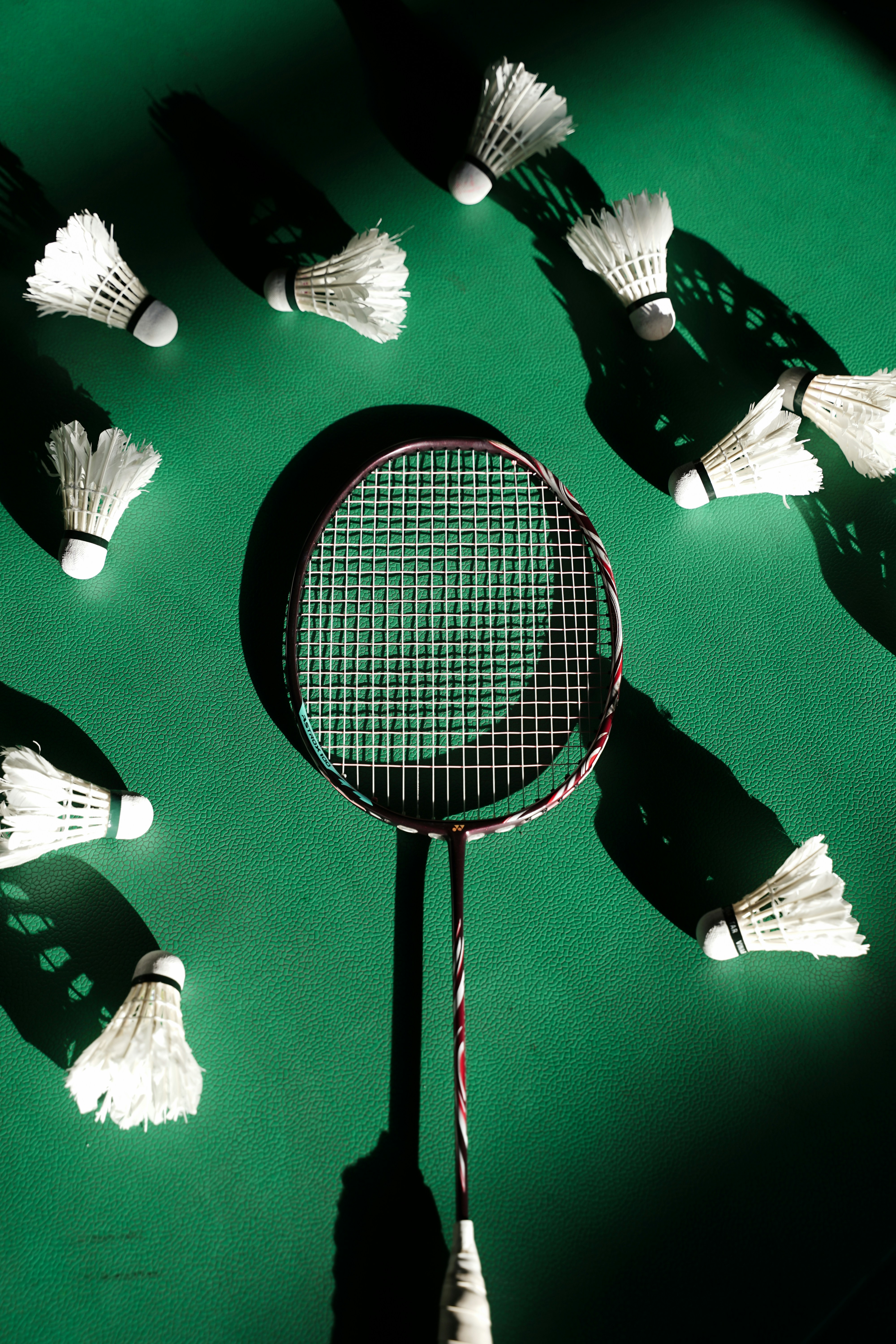 Raquetas de bádminton y volantes esparcidos sobre la superficie verde.