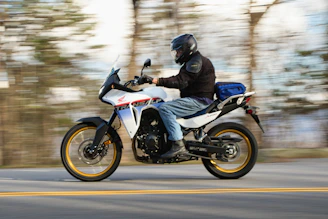 Man riding a white adventure motorcycle on a road.