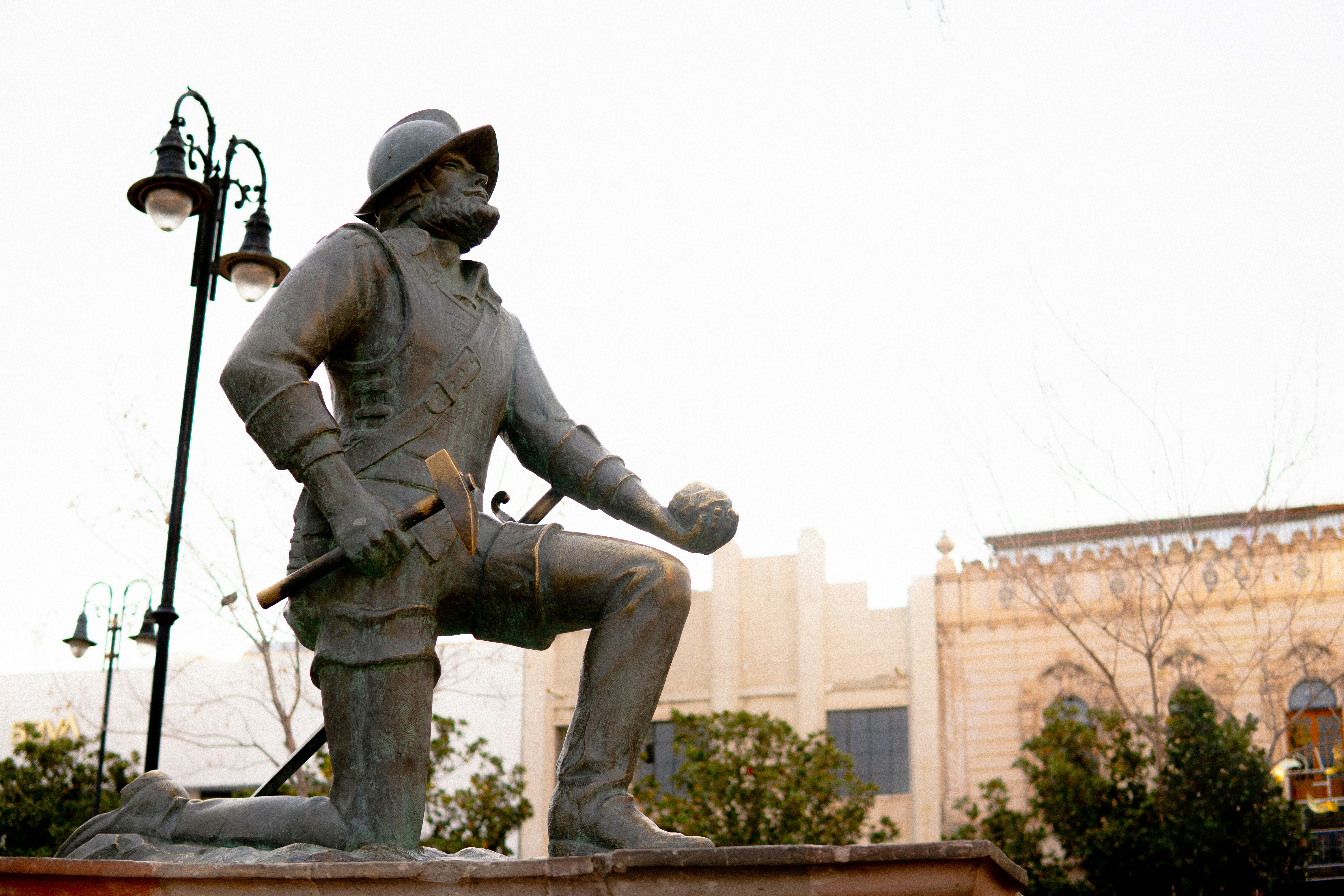 Bronze statue of a kneeling conquistador holding a sphere