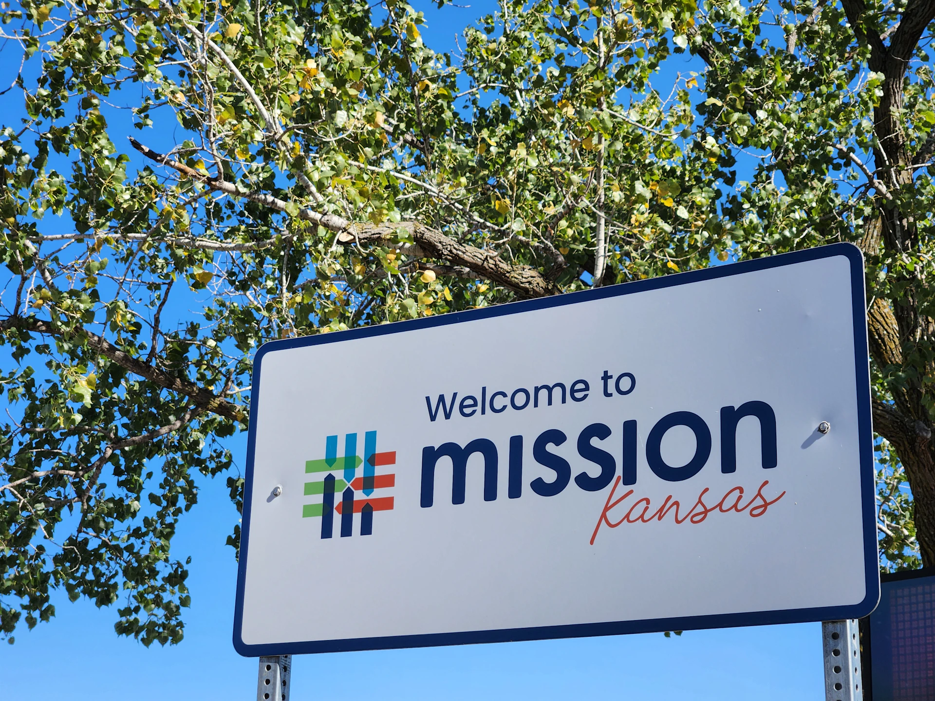 Welcome to mission, kansas sign with trees.